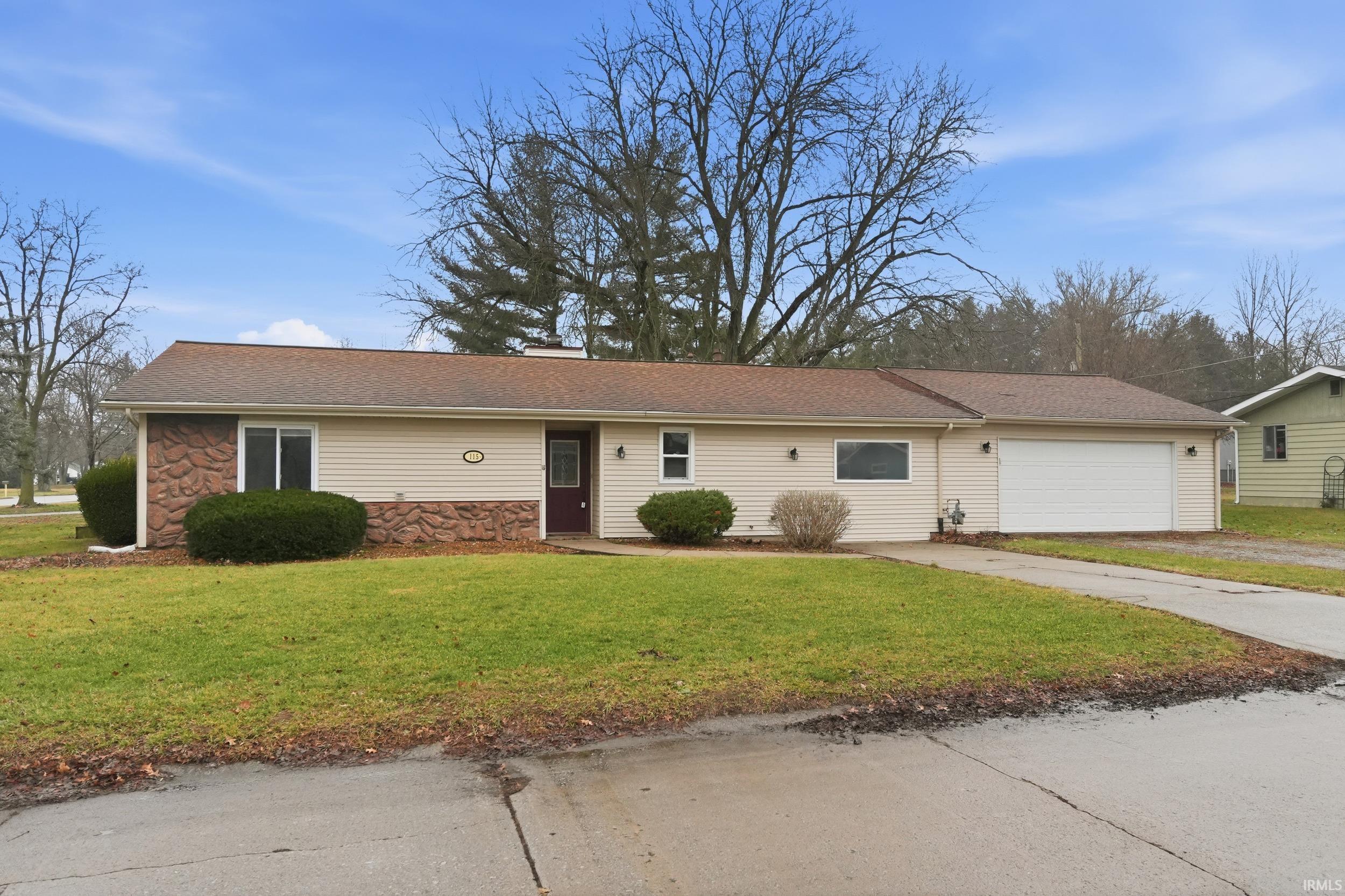 Ranch-style home with a front lawn, stone siding, a garage, driveway, and a shingled roof