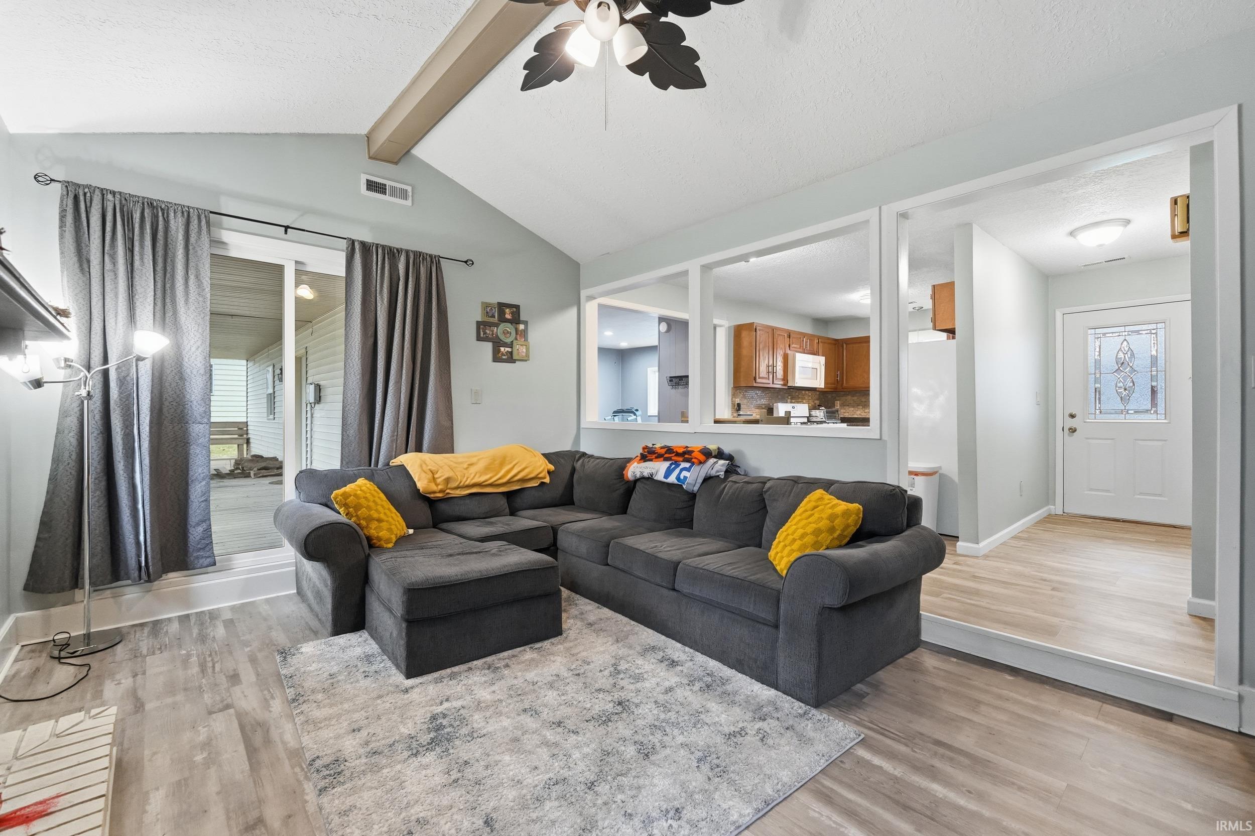 Living area with light wood-style flooring, a ceiling fan, a textured ceiling, and healthy amount of natural light
