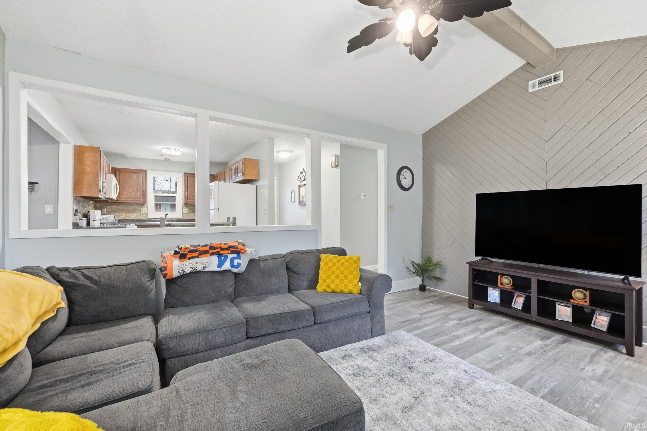 Living area with an accent wall, light wood-style floors, ceiling fan, and wooden walls