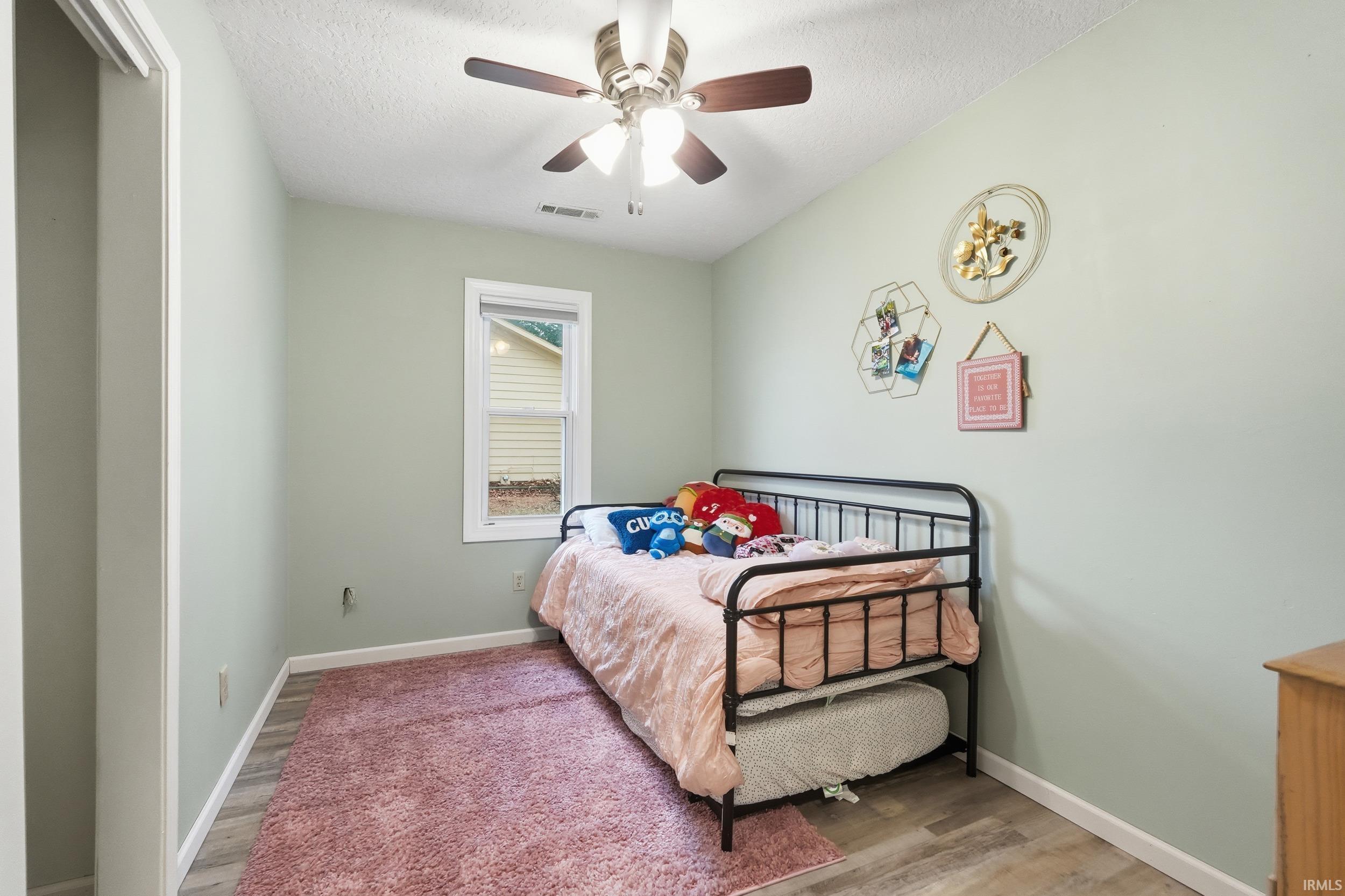 Bedroom featuring a ceiling fan, light wood finished floors, and a textured ceiling