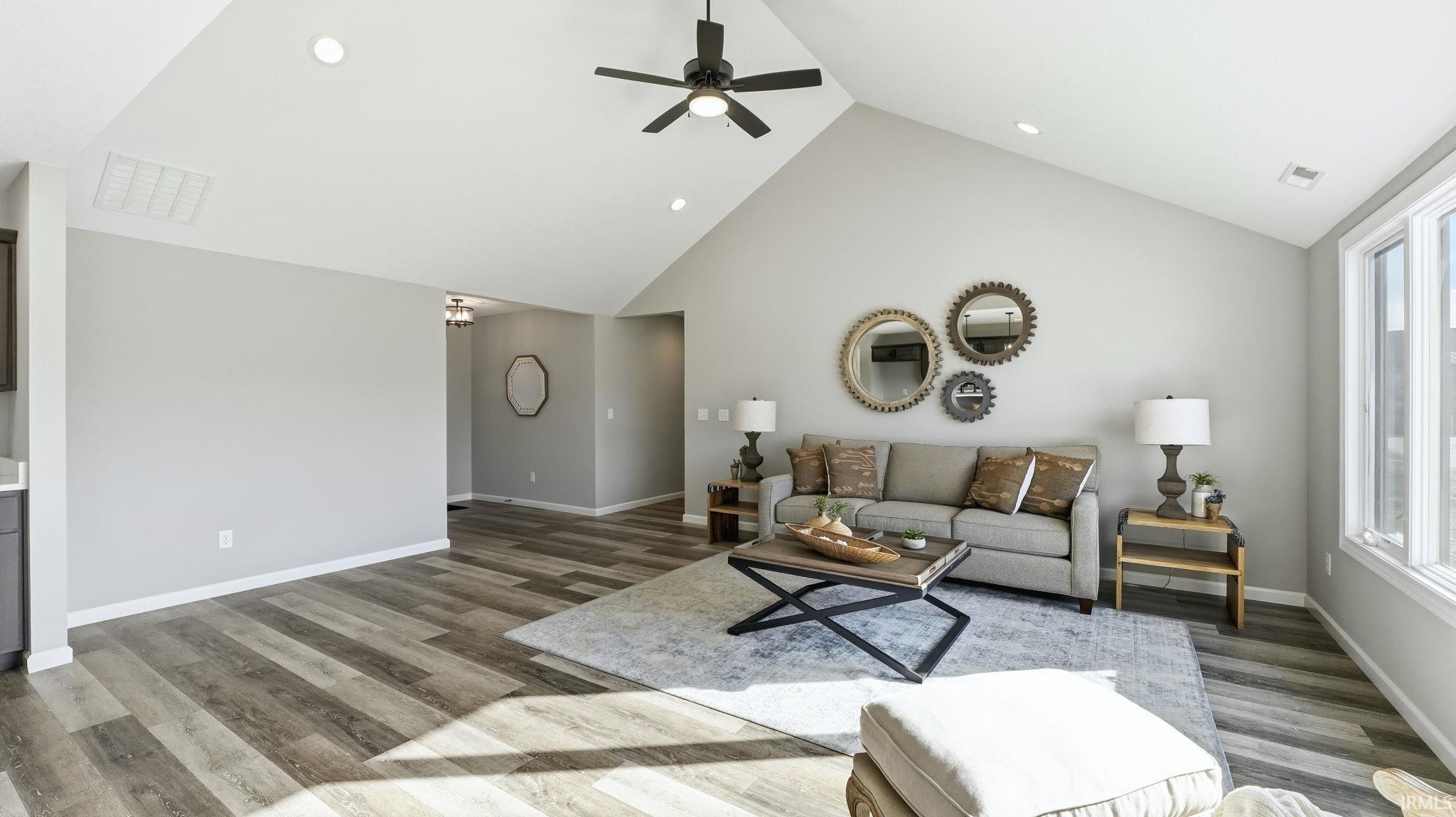 Living room featuring high vaulted ceiling, light wood-style flooring, a ceiling fan, and recessed lighting