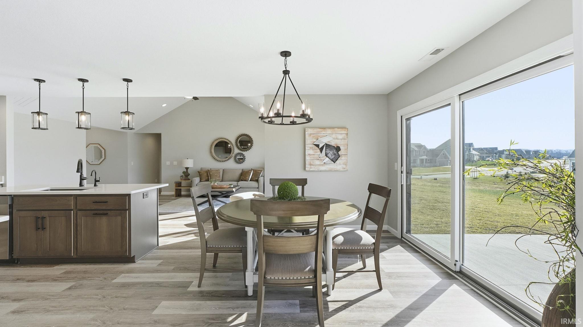 Dining area featuring vaulted ceiling, a chandelier, and light wood-style floors