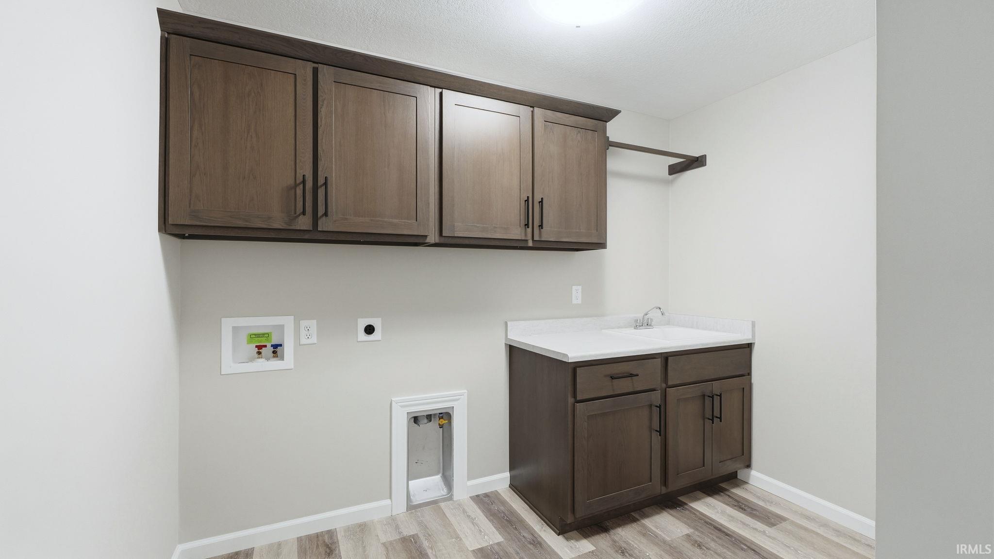 Laundry room with washer hookup, electric dryer hookup, cabinet space, and light wood-type flooring