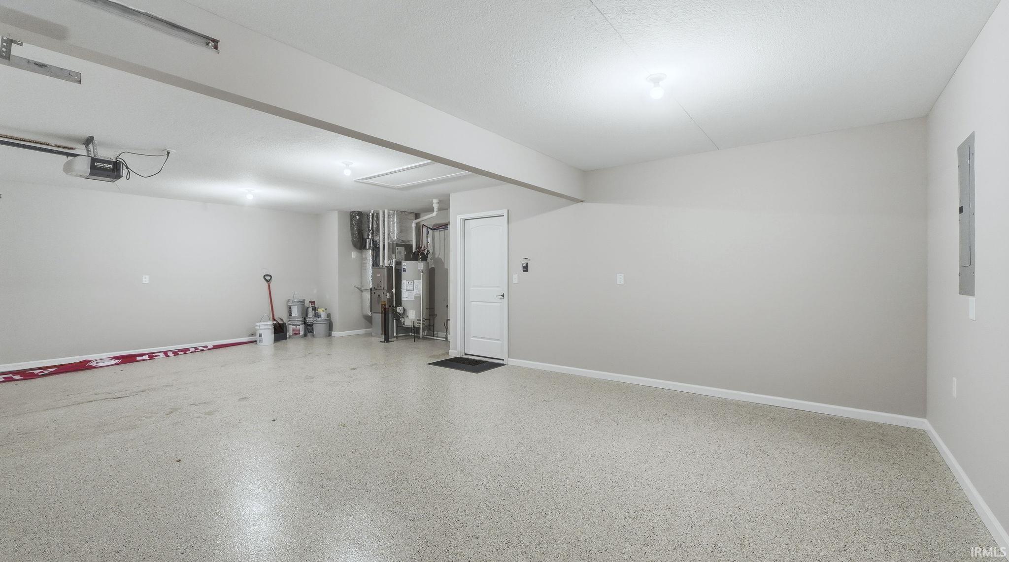 Garage with a garage door opener, water heater, and electric panel