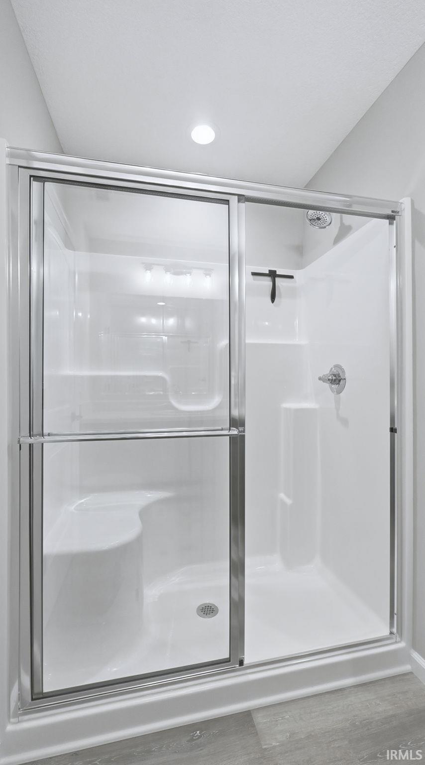 Bathroom featuring a shower stall and wood finished floors
