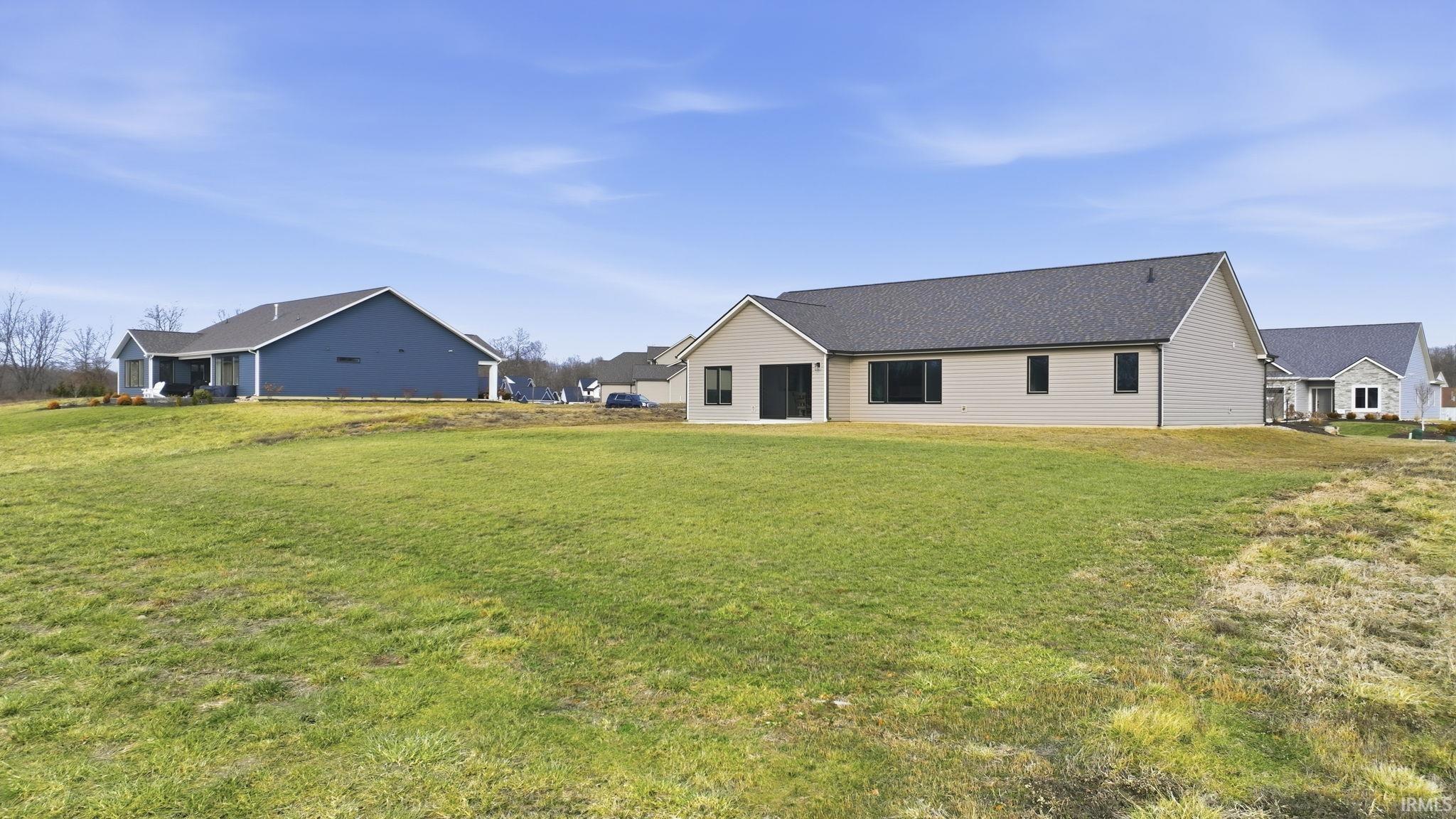Rear view of property featuring a yard and roof with shingles