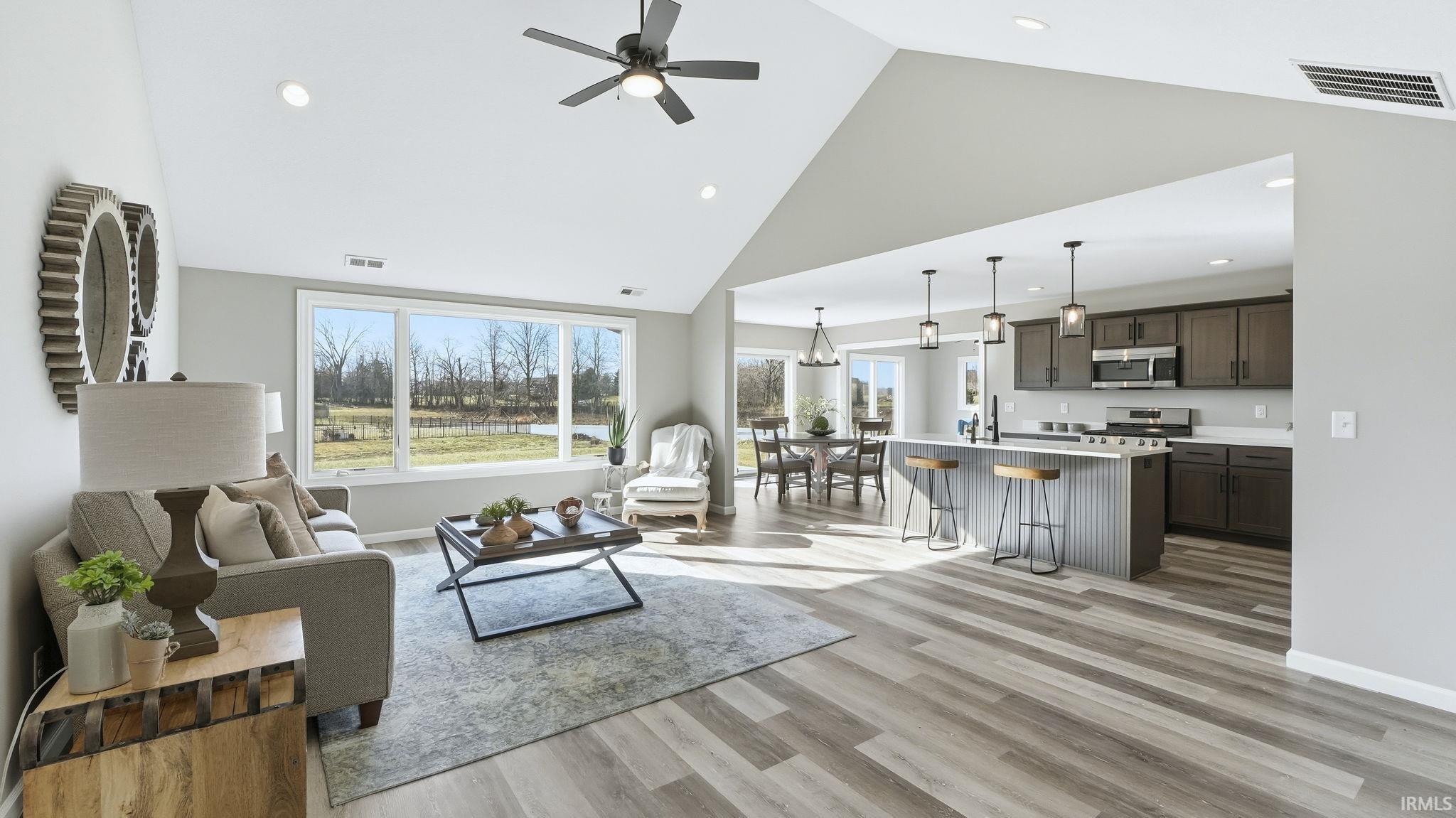 Living area with high vaulted ceiling, light wood finished floors, ceiling fan, and recessed lighting