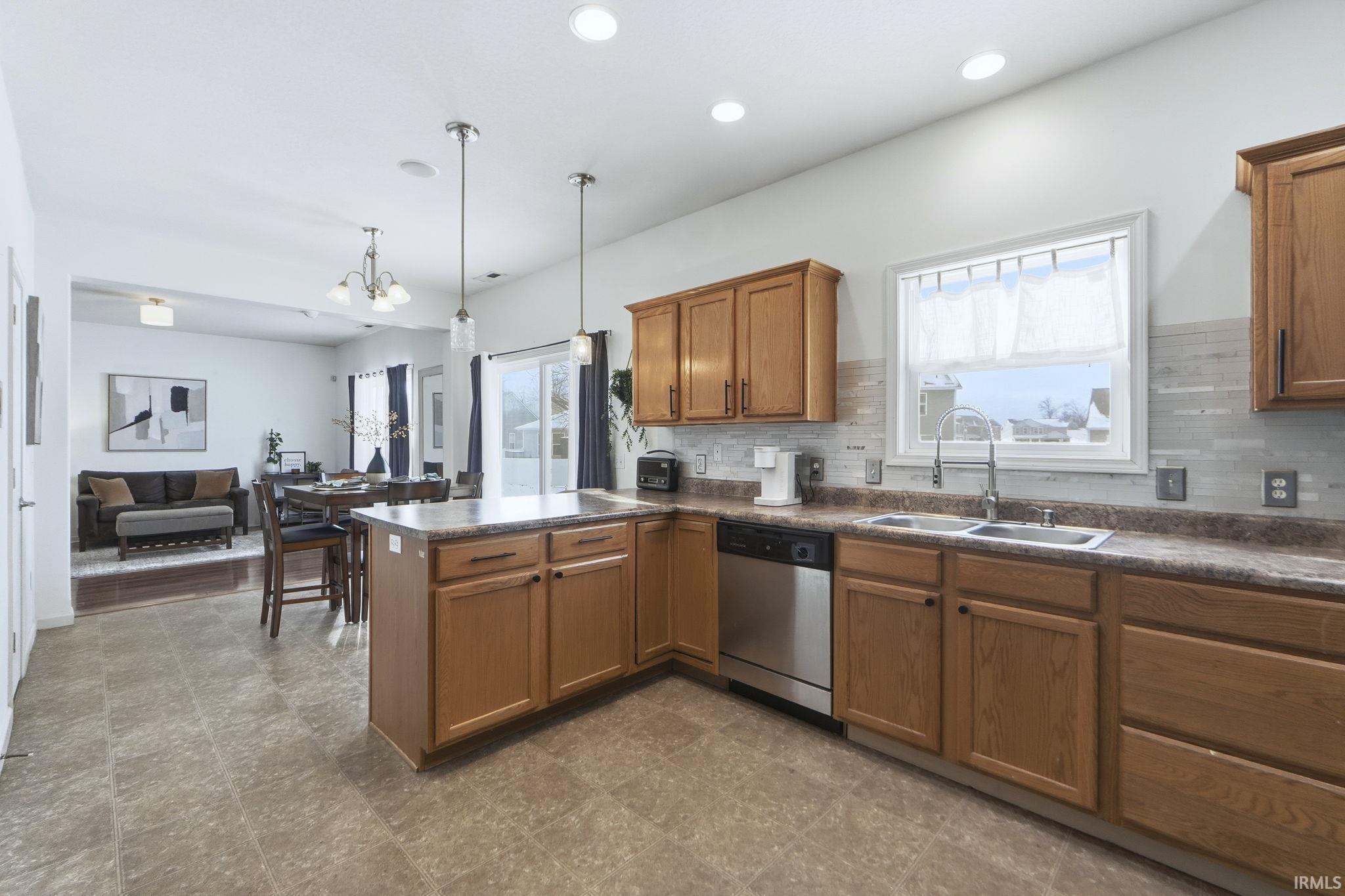 Kitchen with dark countertops, brown cabinets, a peninsula, backsplash, and pendant lighting