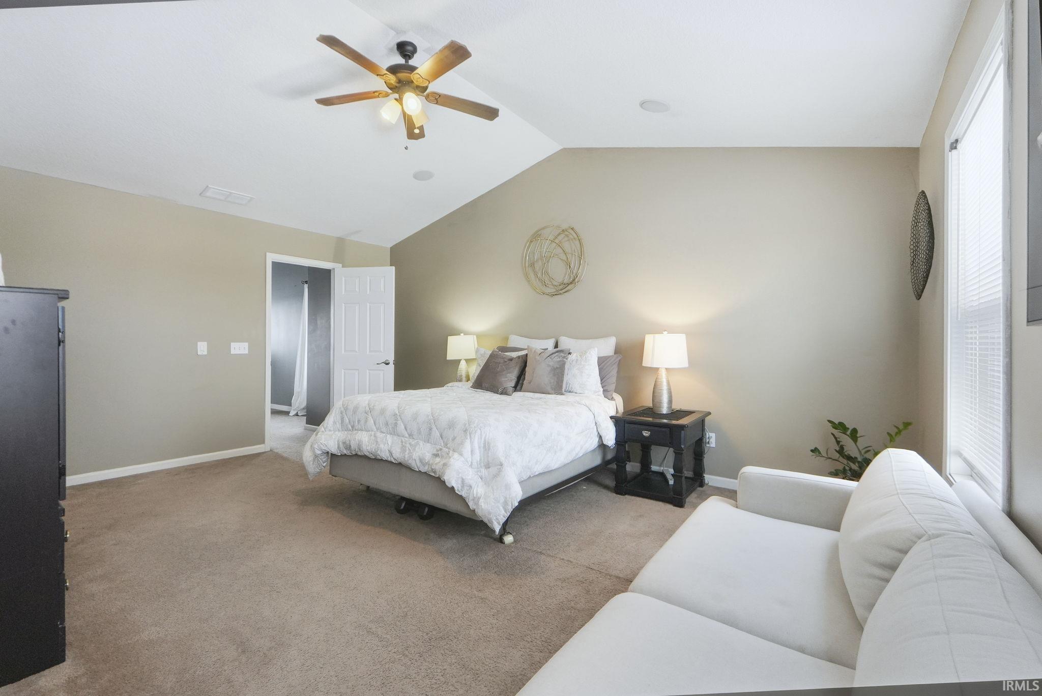 Carpeted bedroom with vaulted ceiling and ceiling fan