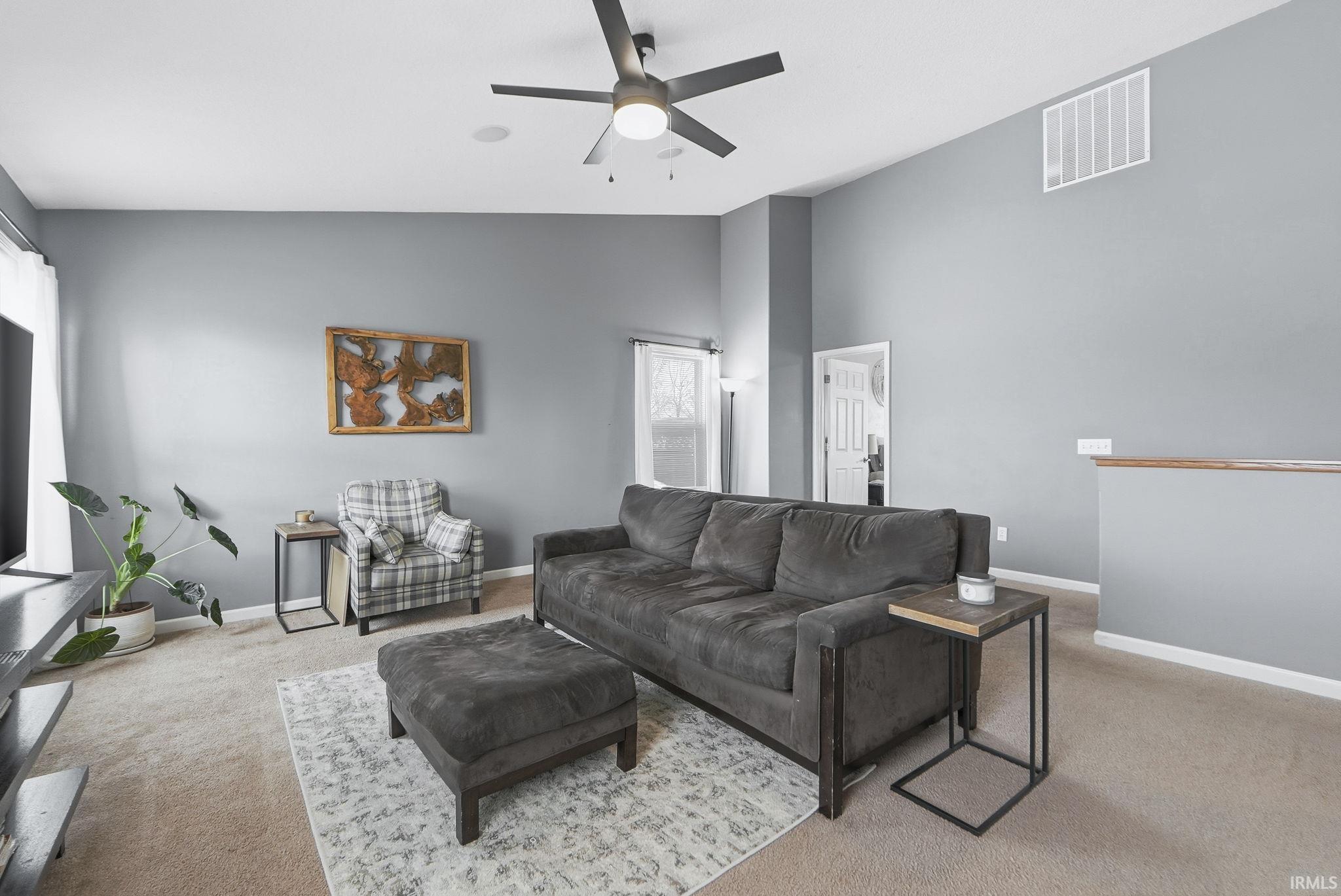 Living area featuring carpet, lofted ceiling, and ceiling fan