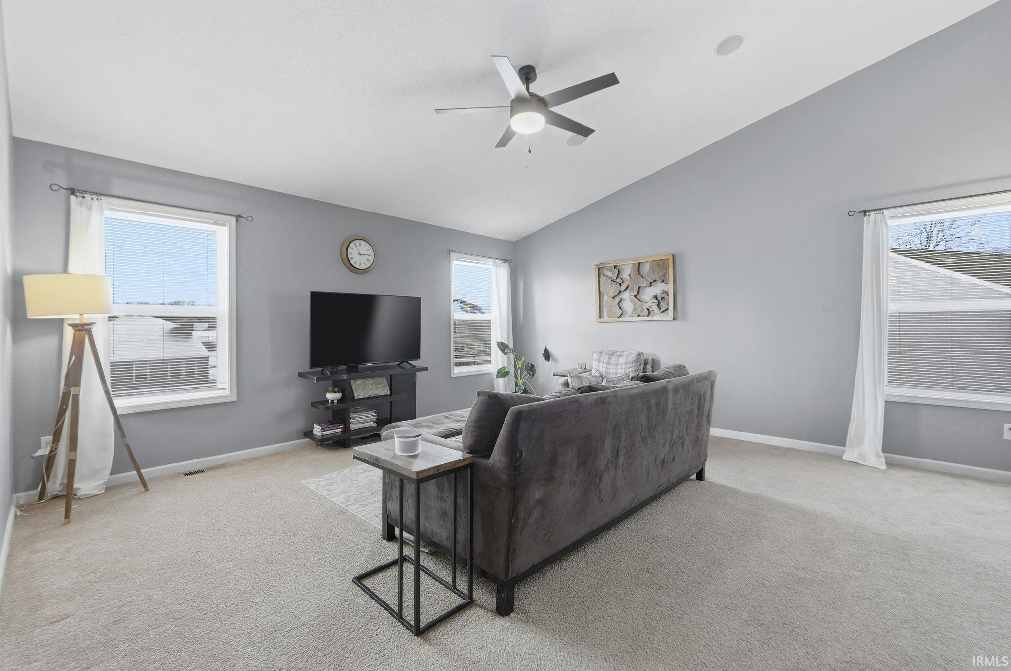 Living room featuring carpet flooring, lofted ceiling, healthy amount of natural light, and ceiling fan