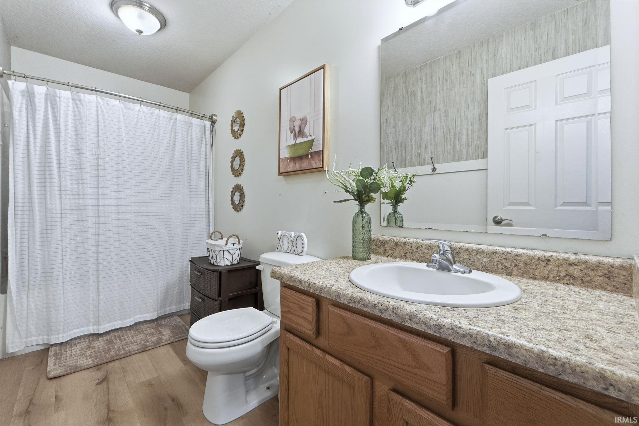 Bathroom with vanity, light wood-style floors, and shower / bath combination with curtain