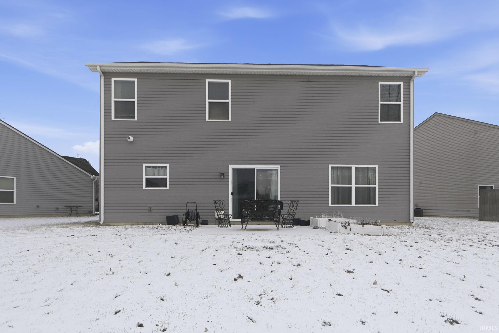 Snow covered rear of property featuring a patio
