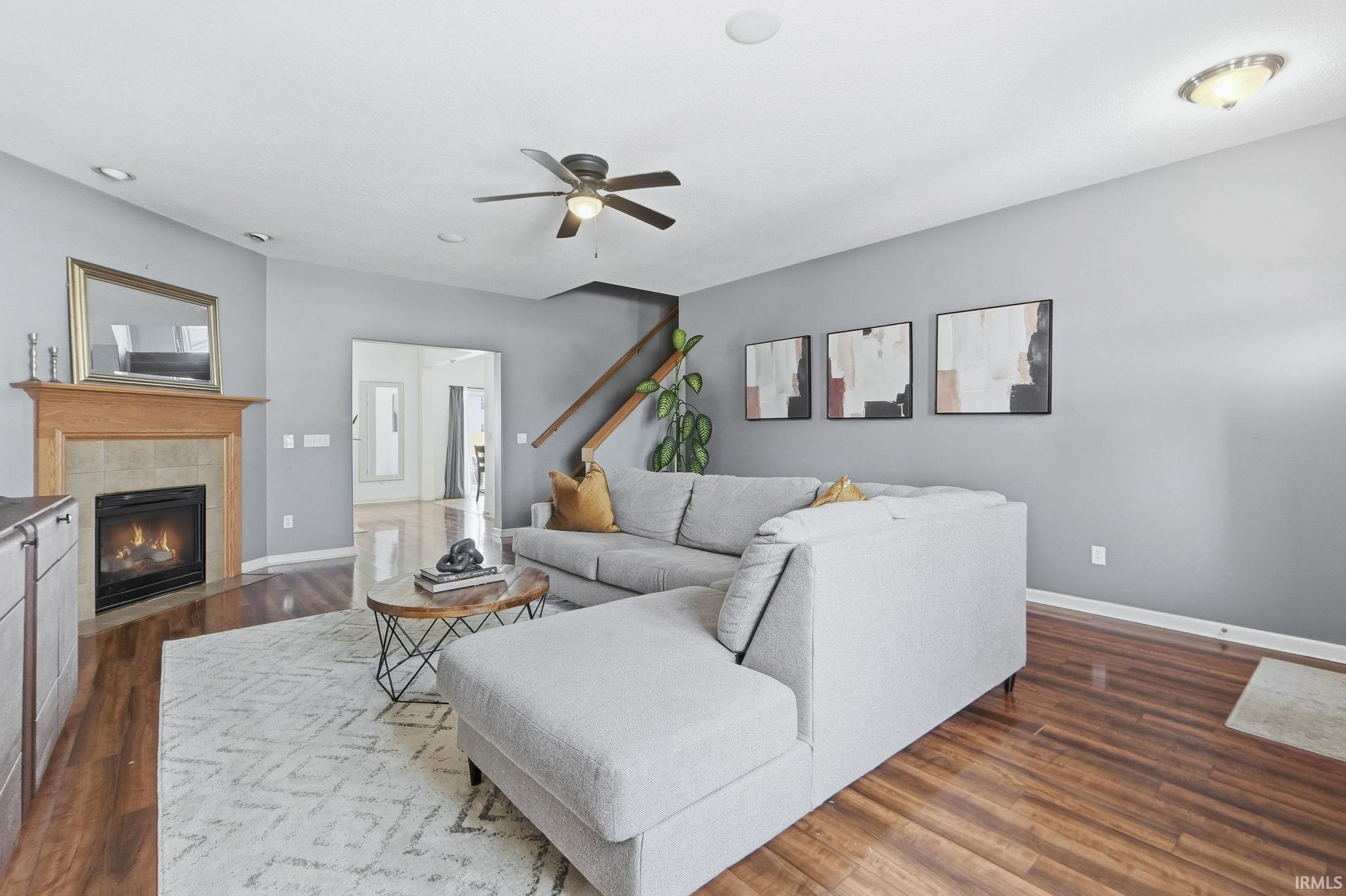 Living area featuring a tile fireplace, dark wood finished floors, and a ceiling fan