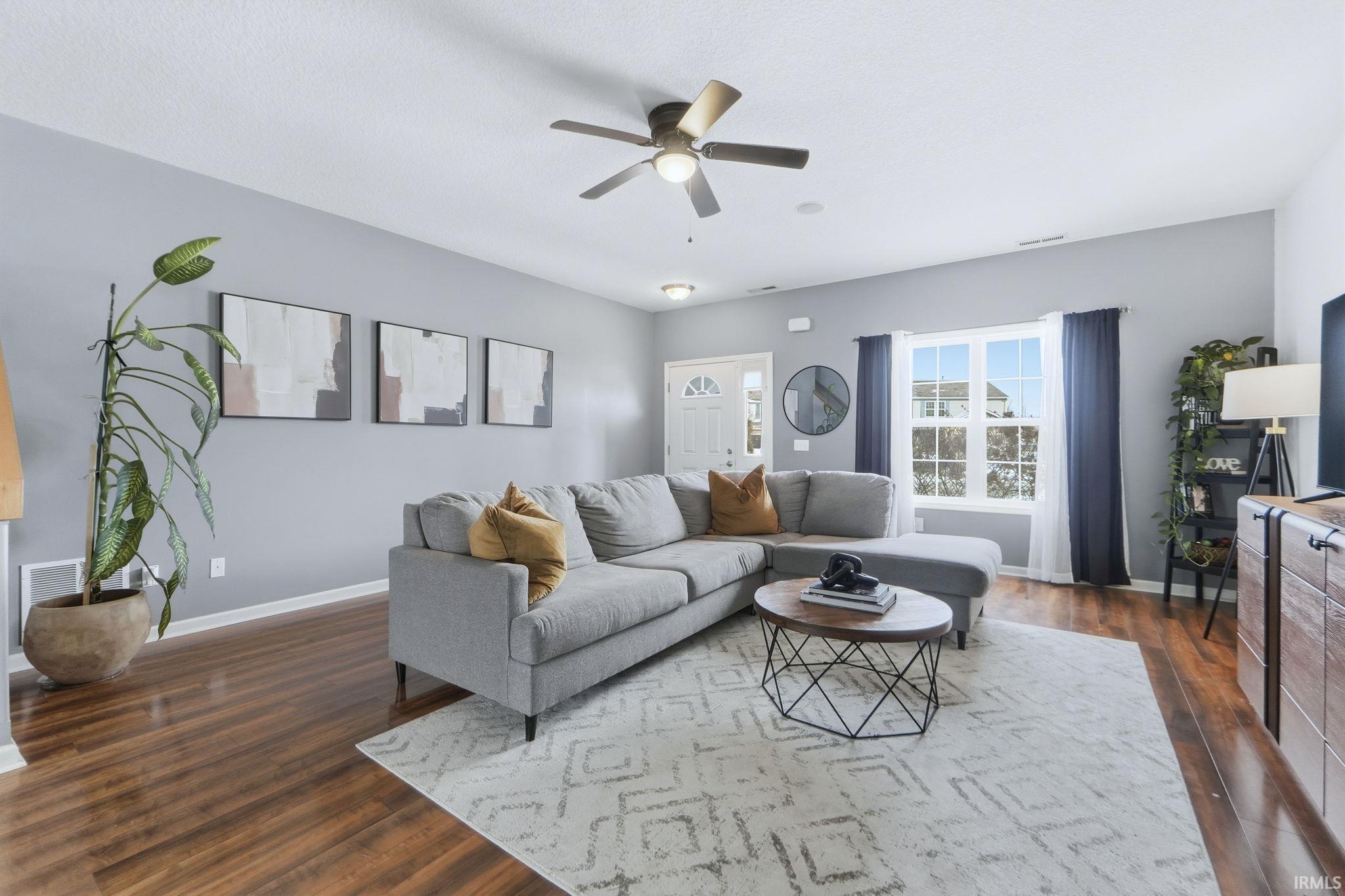 Living room with ceiling fan and dark wood-style flooring