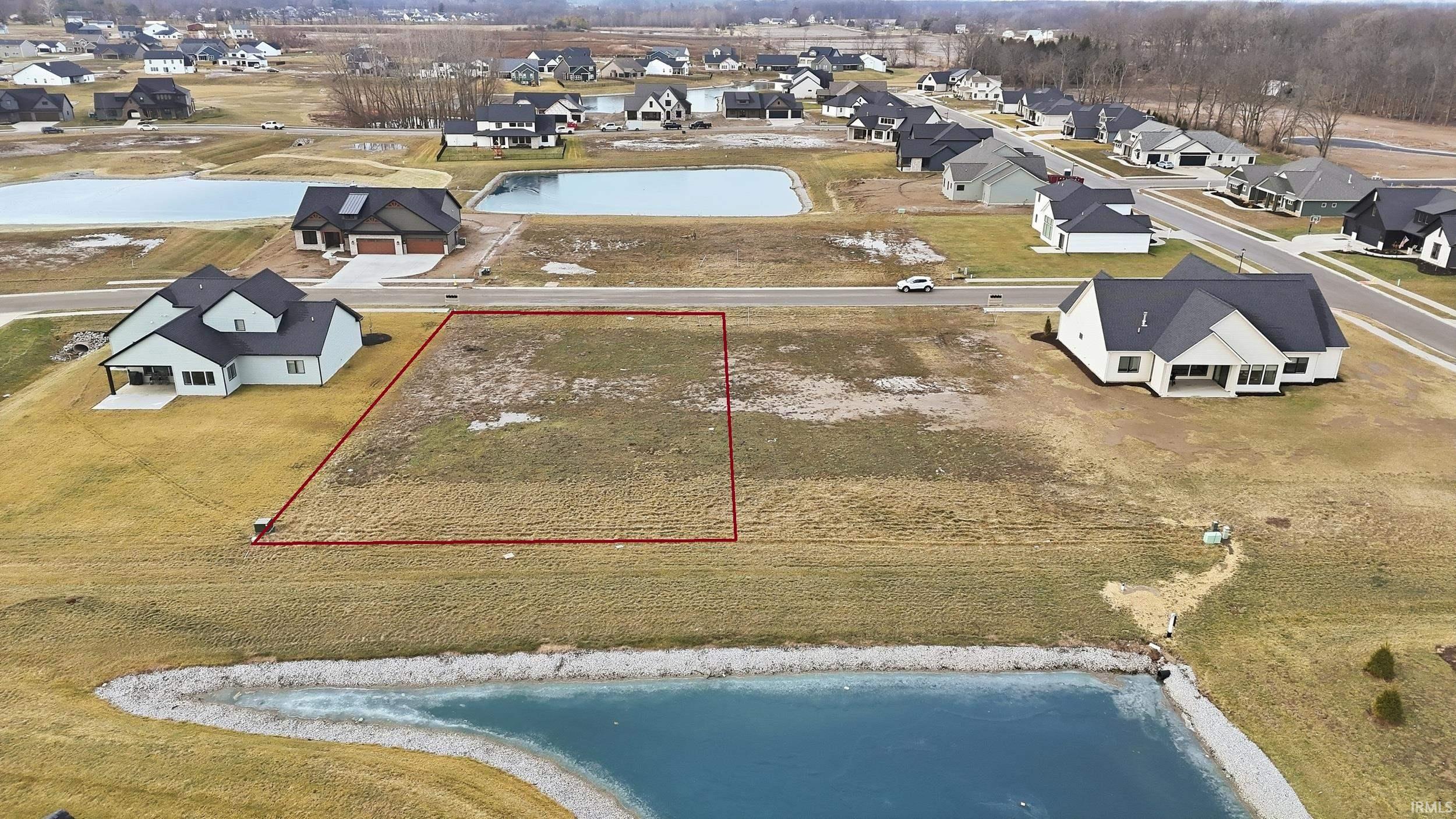 Aerial view of residential area with property parcel outlined and a nearby body of water