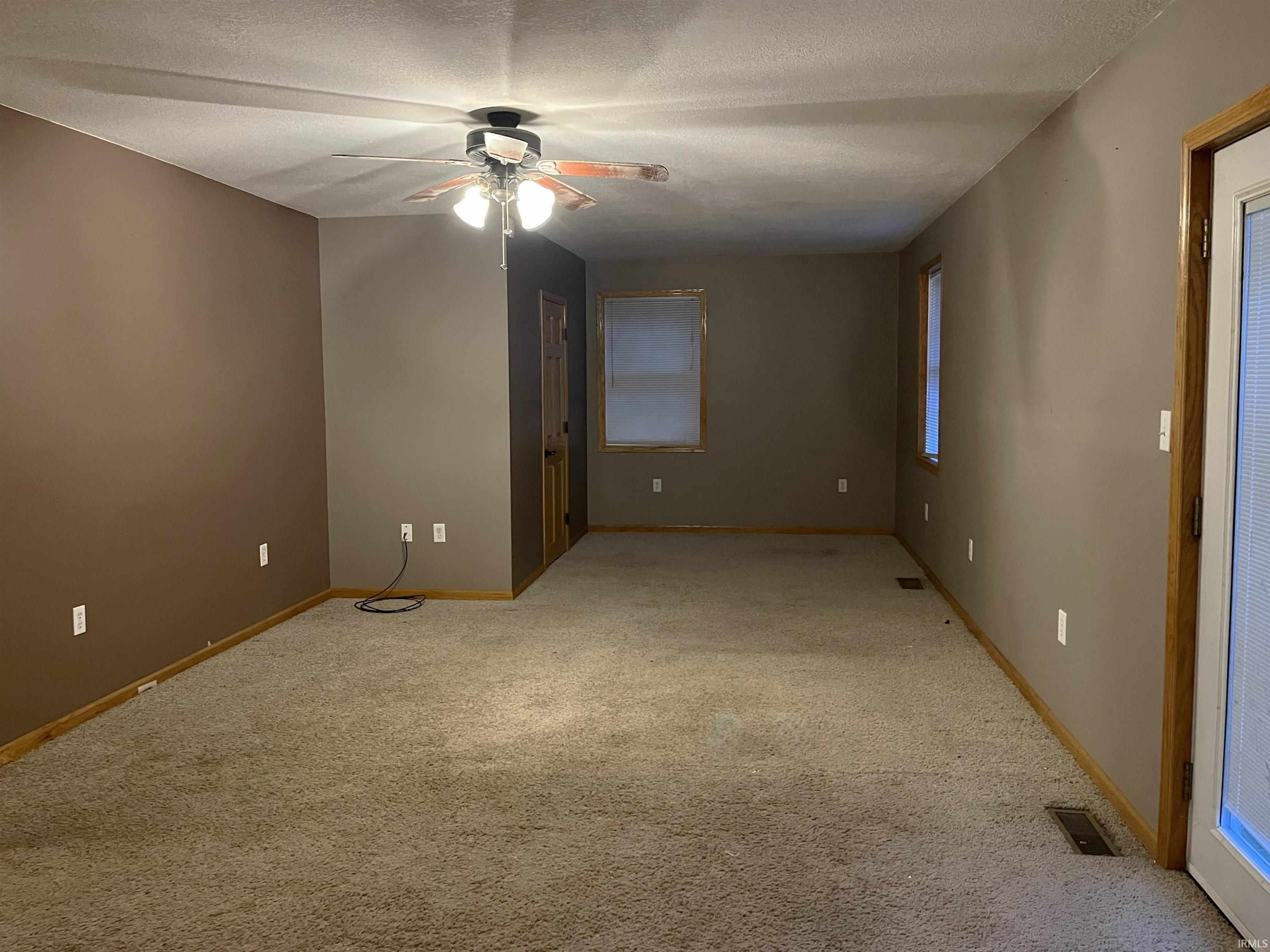 Unfurnished room with light carpet, a textured ceiling, and a ceiling fan