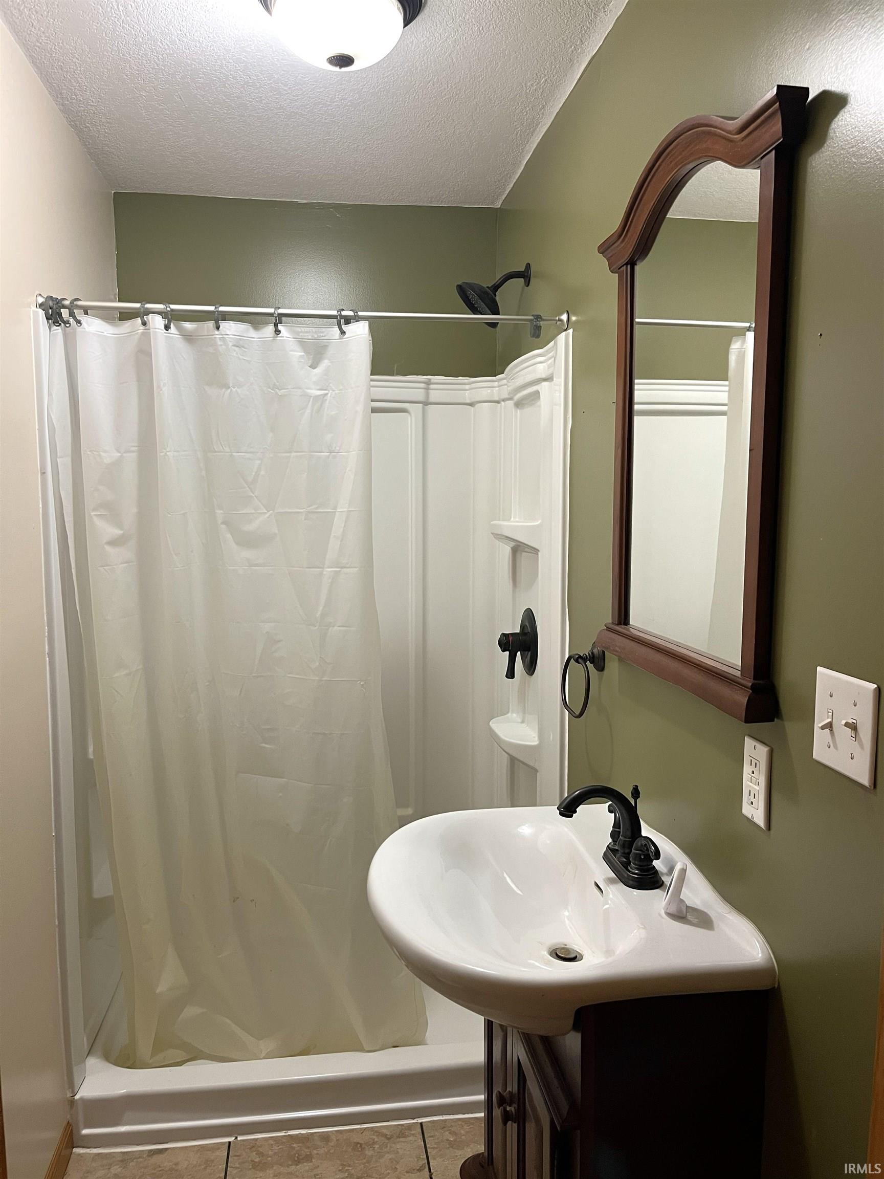 Bathroom with a textured ceiling, vanity, and tile patterned floors