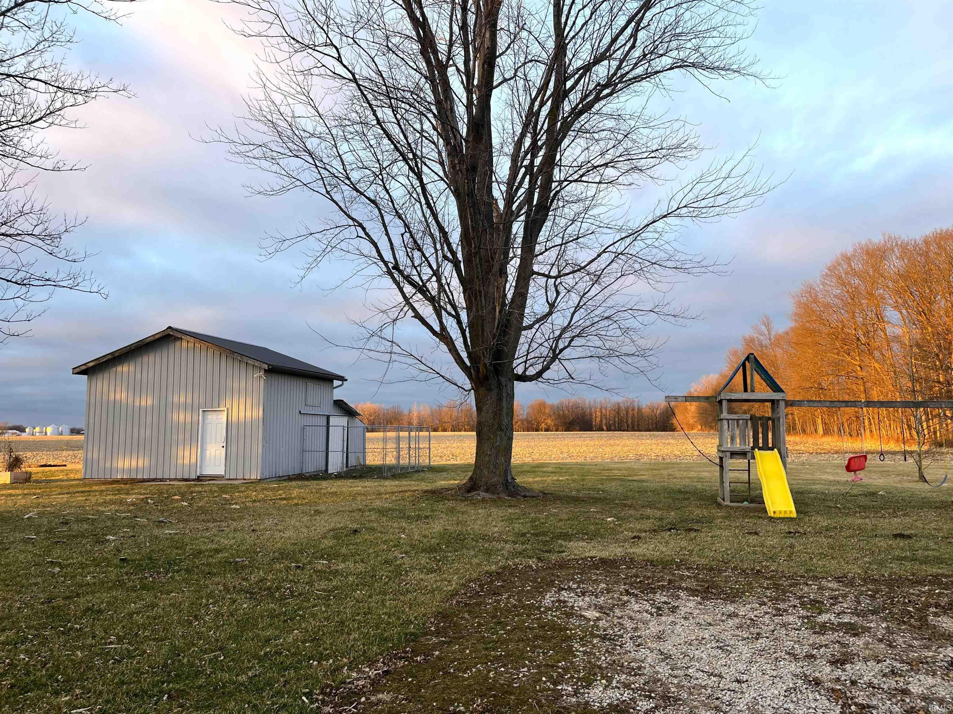 View of grassy yard featuring a playground and an outbuilding