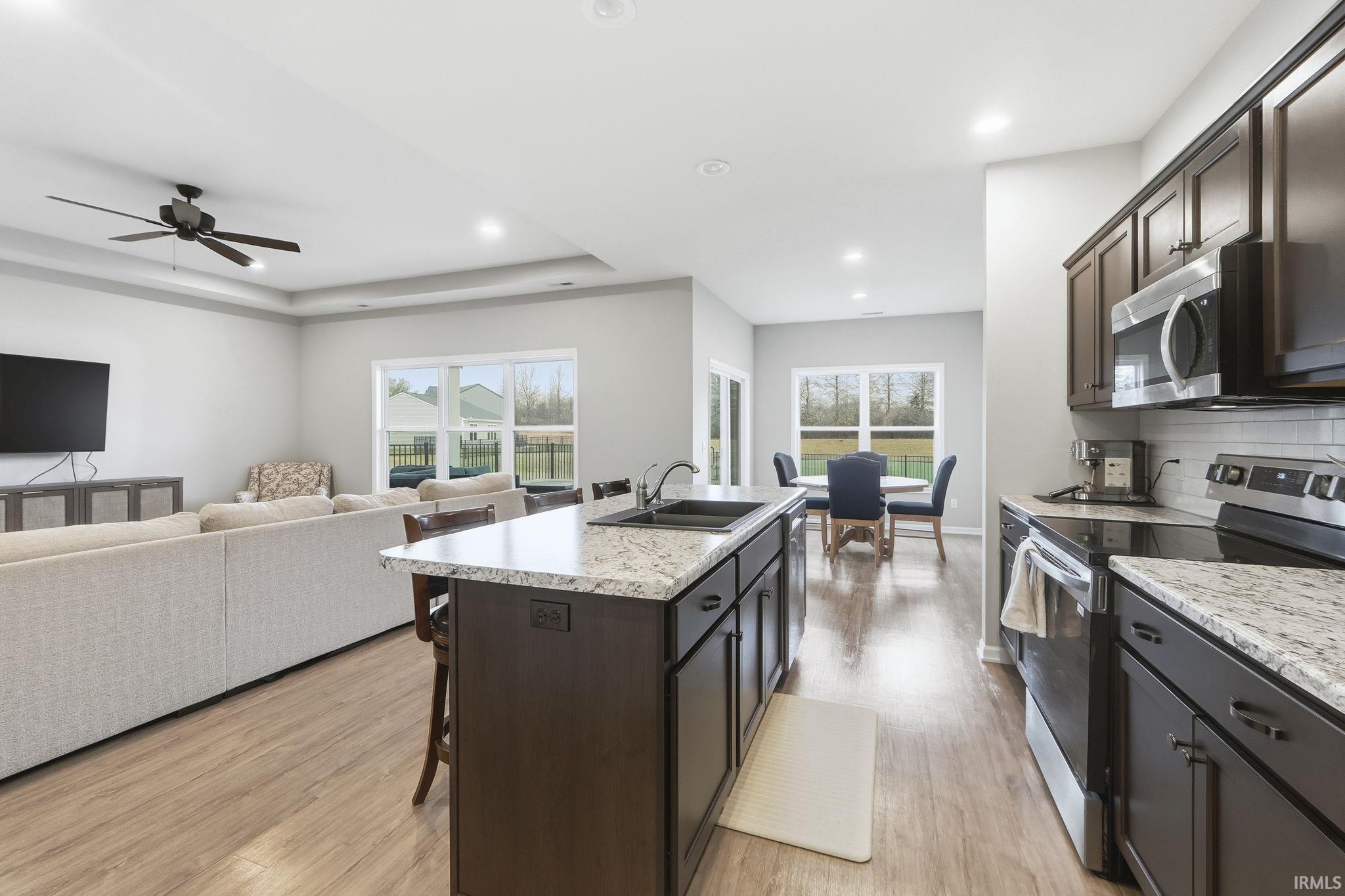 Kitchen featuring stainless steel appliances, dark brown cabinets, an island with sink, a kitchen breakfast bar, and recessed lighting