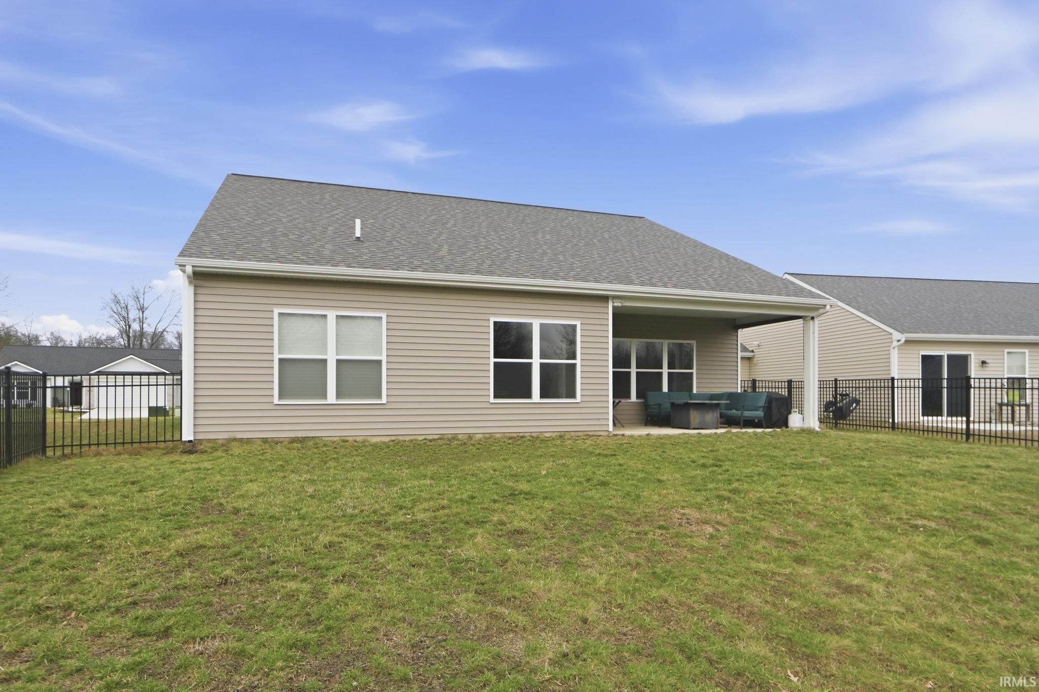 Rear view of house with a fenced backyard, a patio, oil tank, and a shingled roof