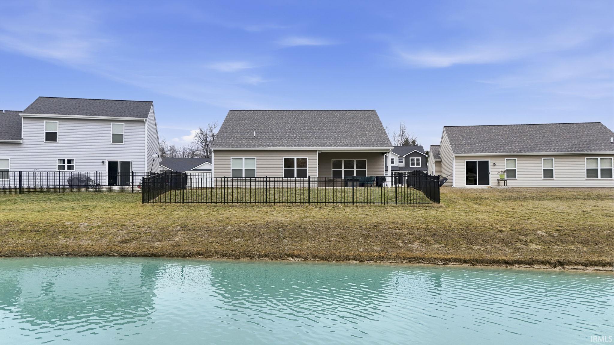 Rear view of house with a water view and a fenced backyard
