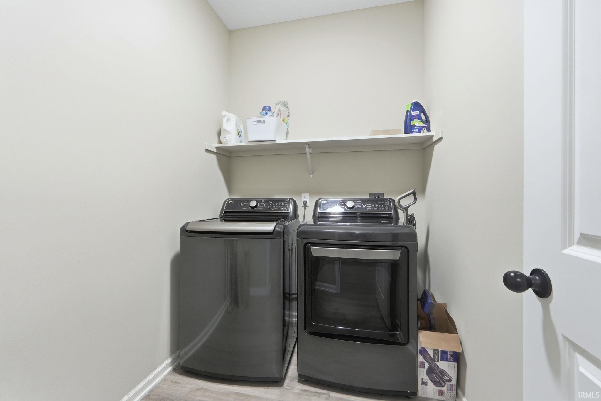 Laundry area with washer and dryer and light wood-type flooring