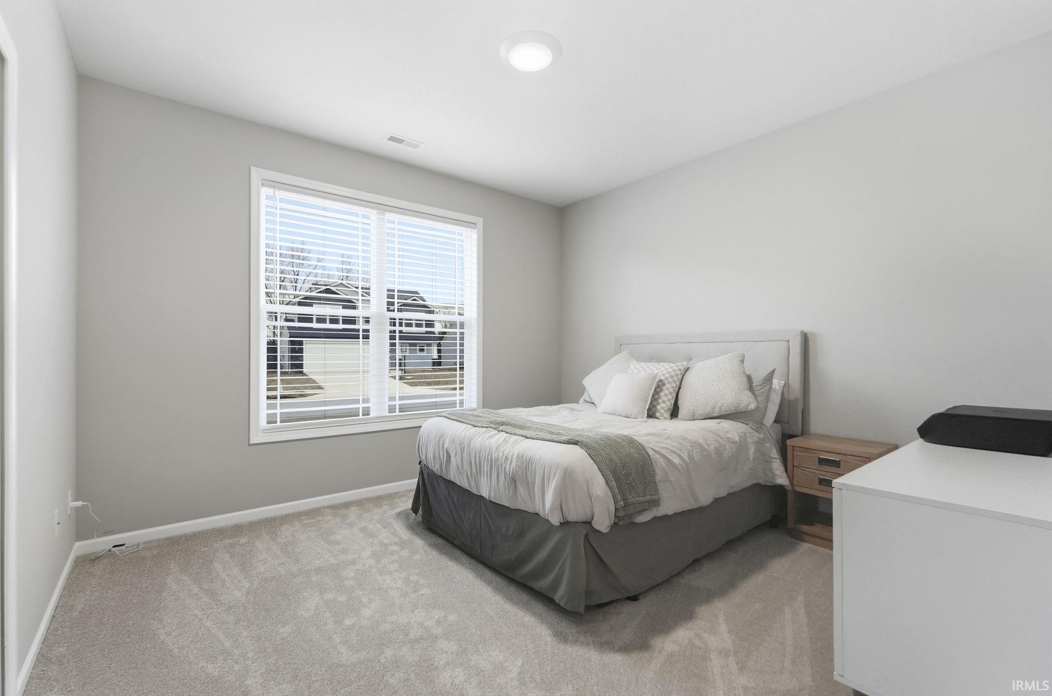 Bedroom featuring light colored carpet and baseboards