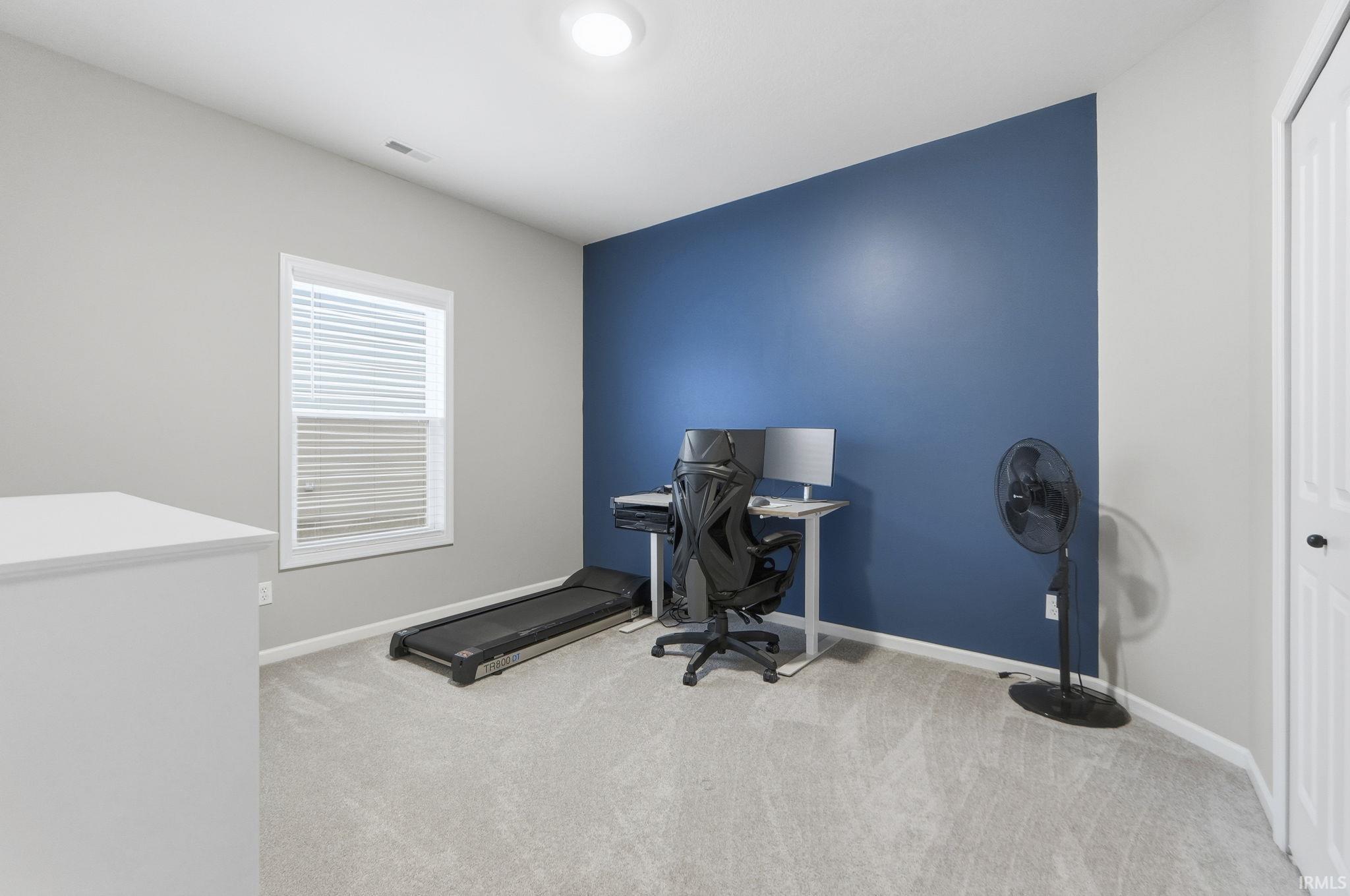 Office space with baseboards and light carpet