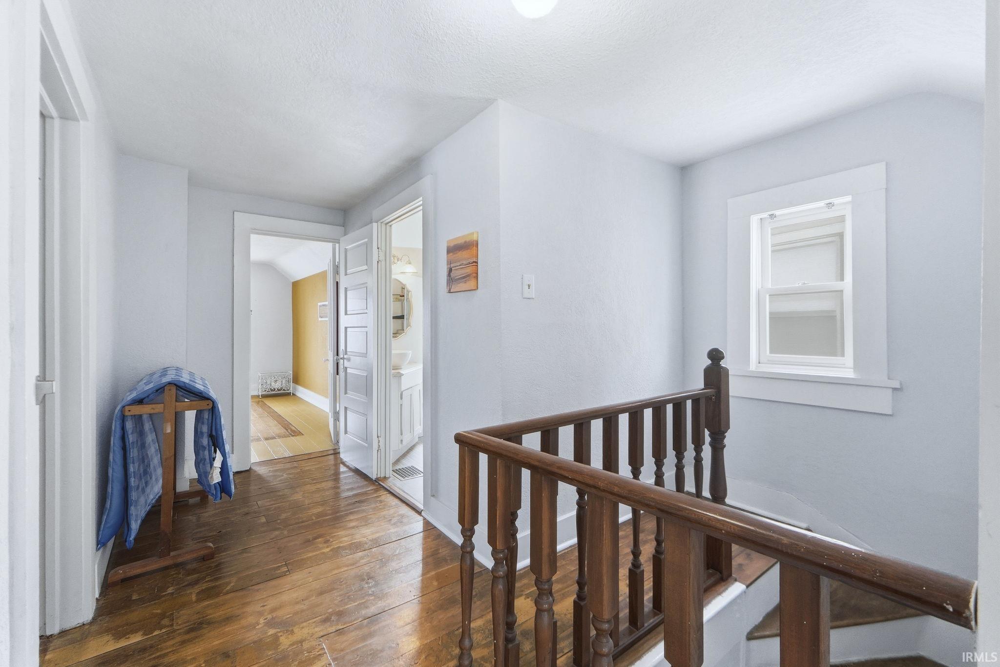 Hall featuring an upstairs landing, dark wood-style flooring, and a textured ceiling