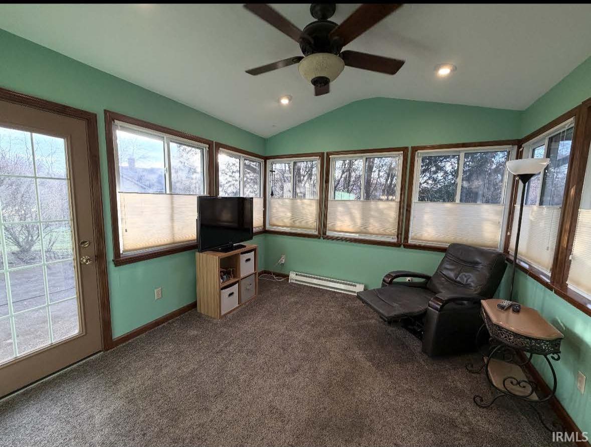 Sunroom / solarium with vaulted ceiling, plenty of natural light, a baseboard radiator, carpet flooring, and recessed lighting