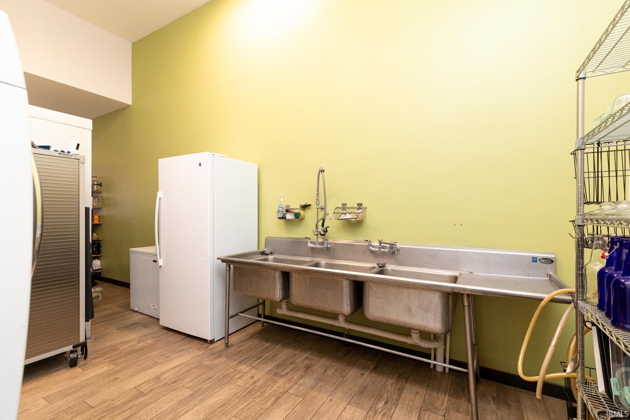 Miscellaneous room featuring light wood-style flooring and a towering ceiling
