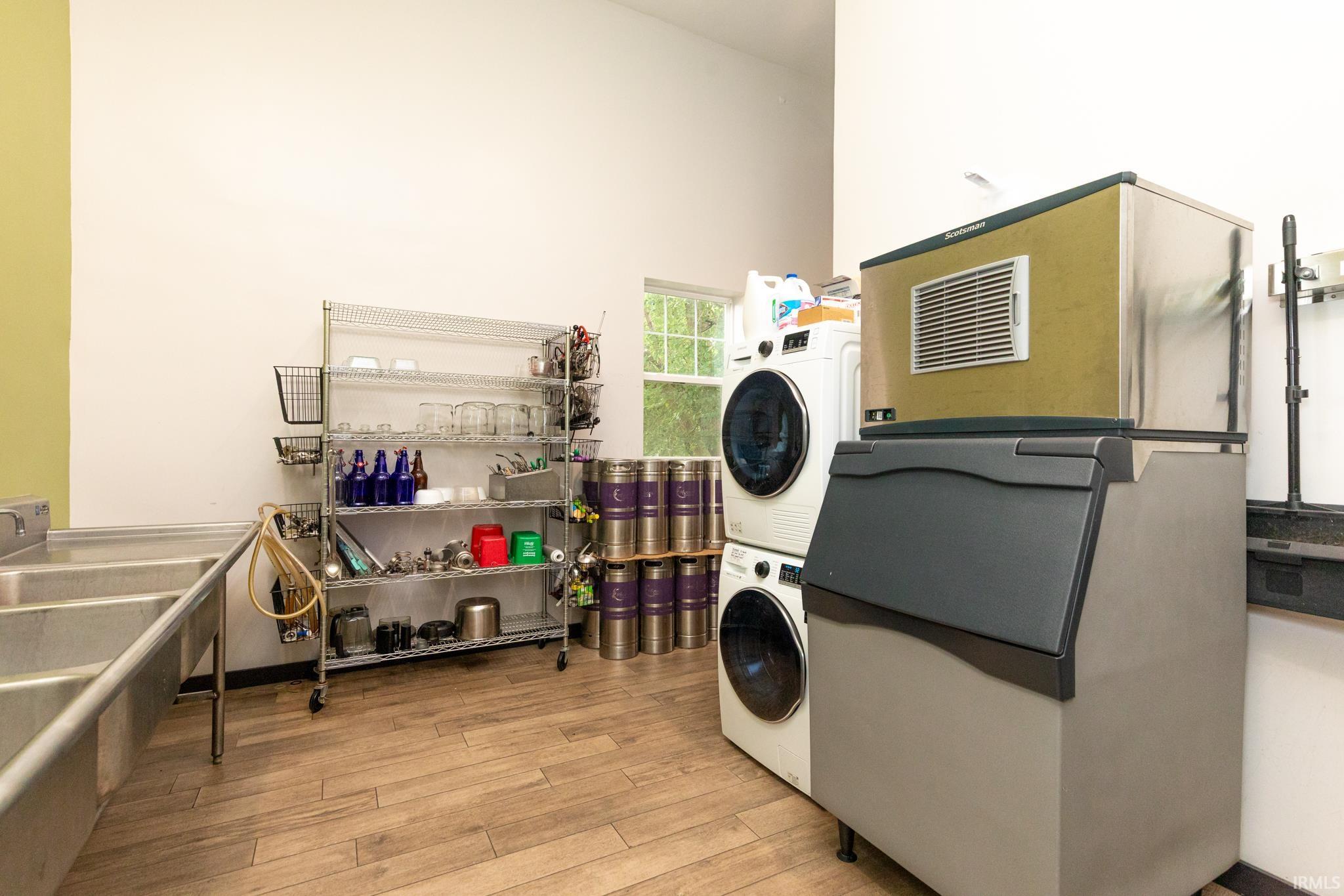 Washroom with stacked washer / drying machine, light wood-style floors, and a towering ceiling