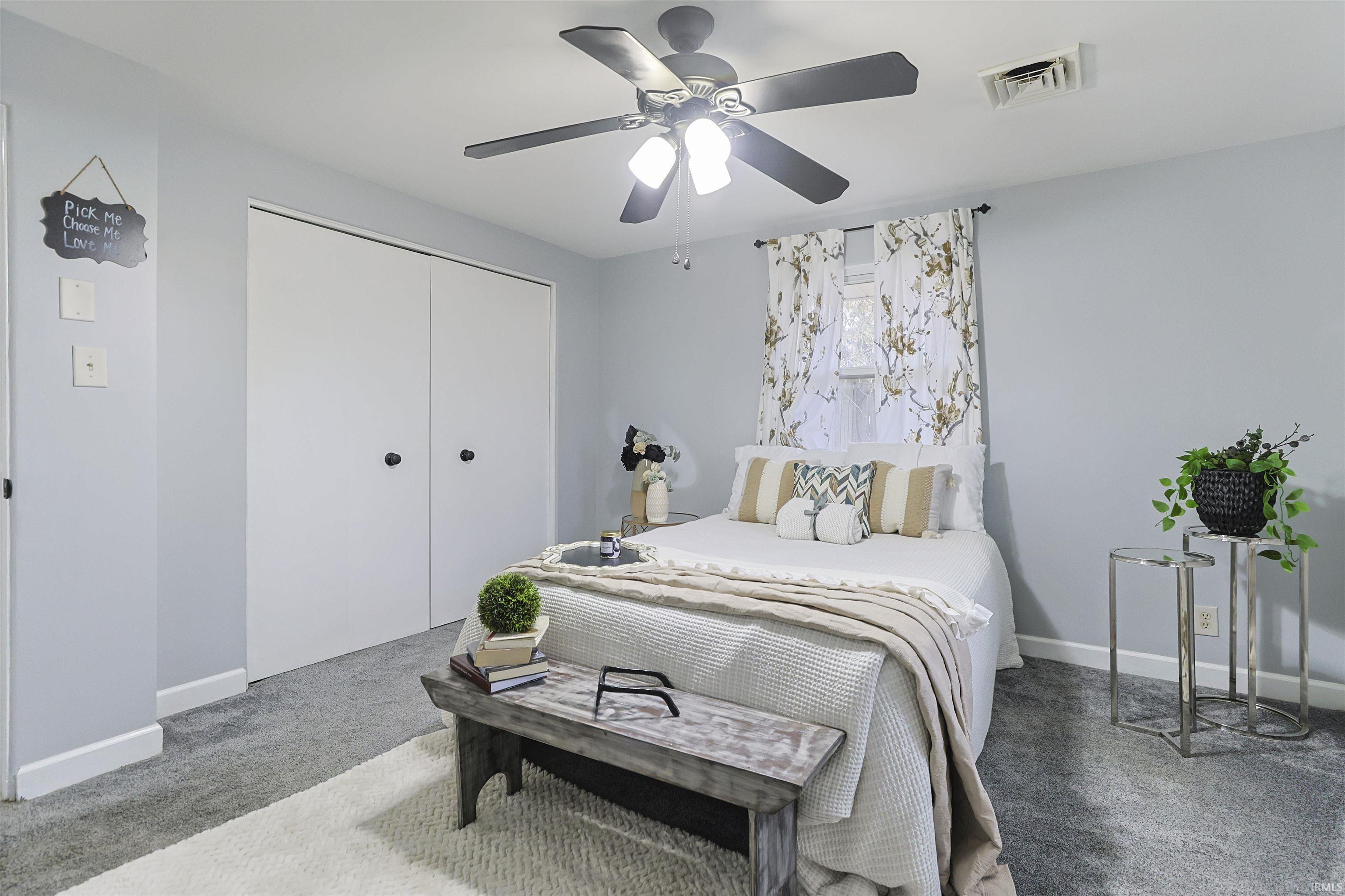 Carpeted bedroom with a ceiling fan and a closet