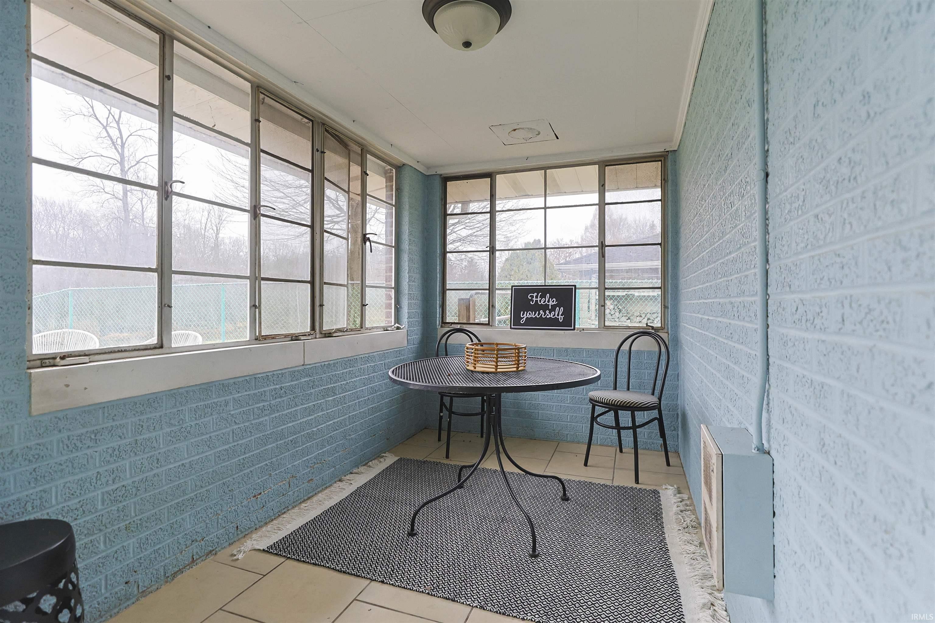 Sunroom featuring brick wall and tile patterned floors