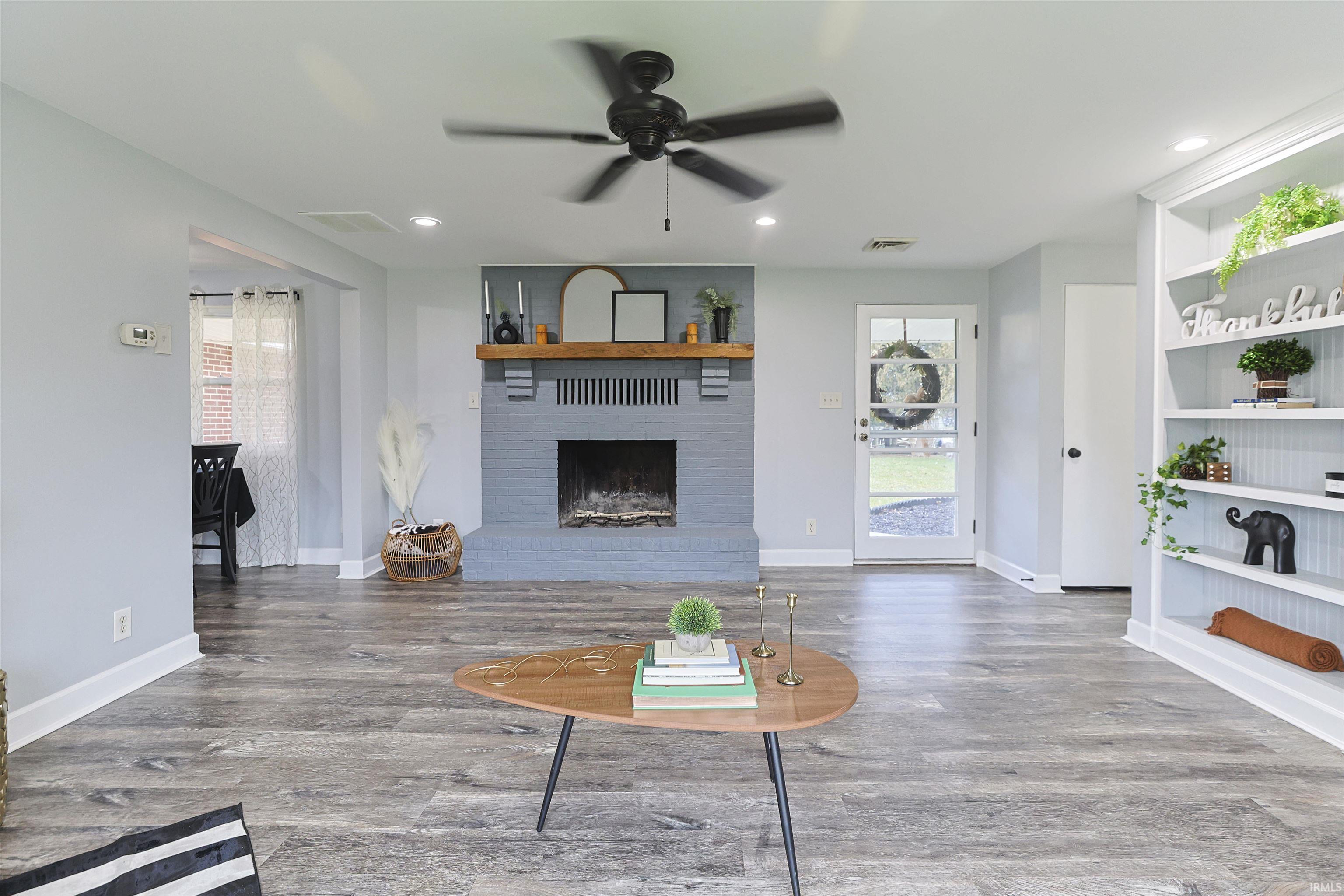 Living room with a ceiling fan, a brick fireplace, wood finished floors, recessed lighting, and built in shelves
