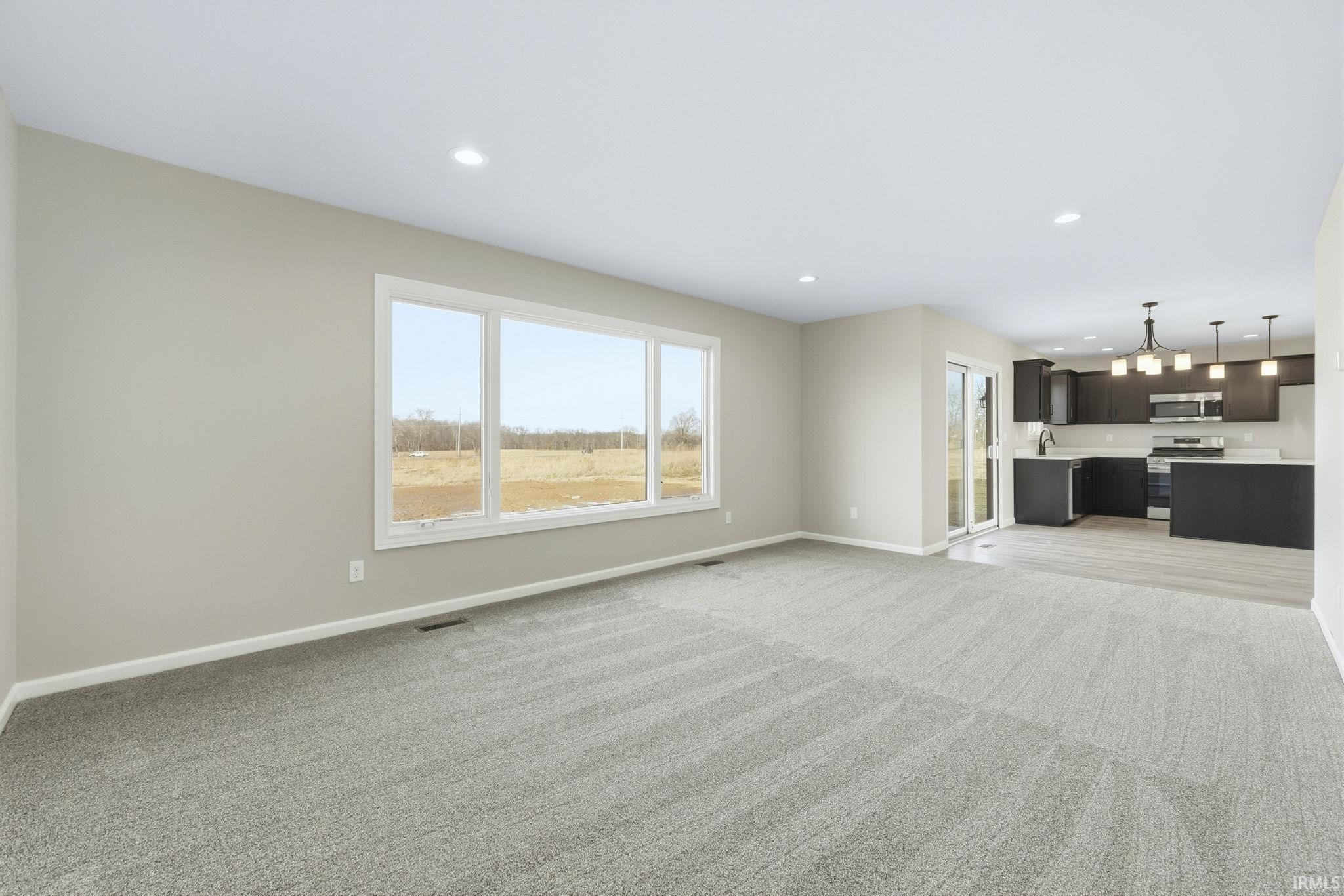 Unfurnished living room featuring healthy amount of natural light, light colored carpet, and recessed lighting