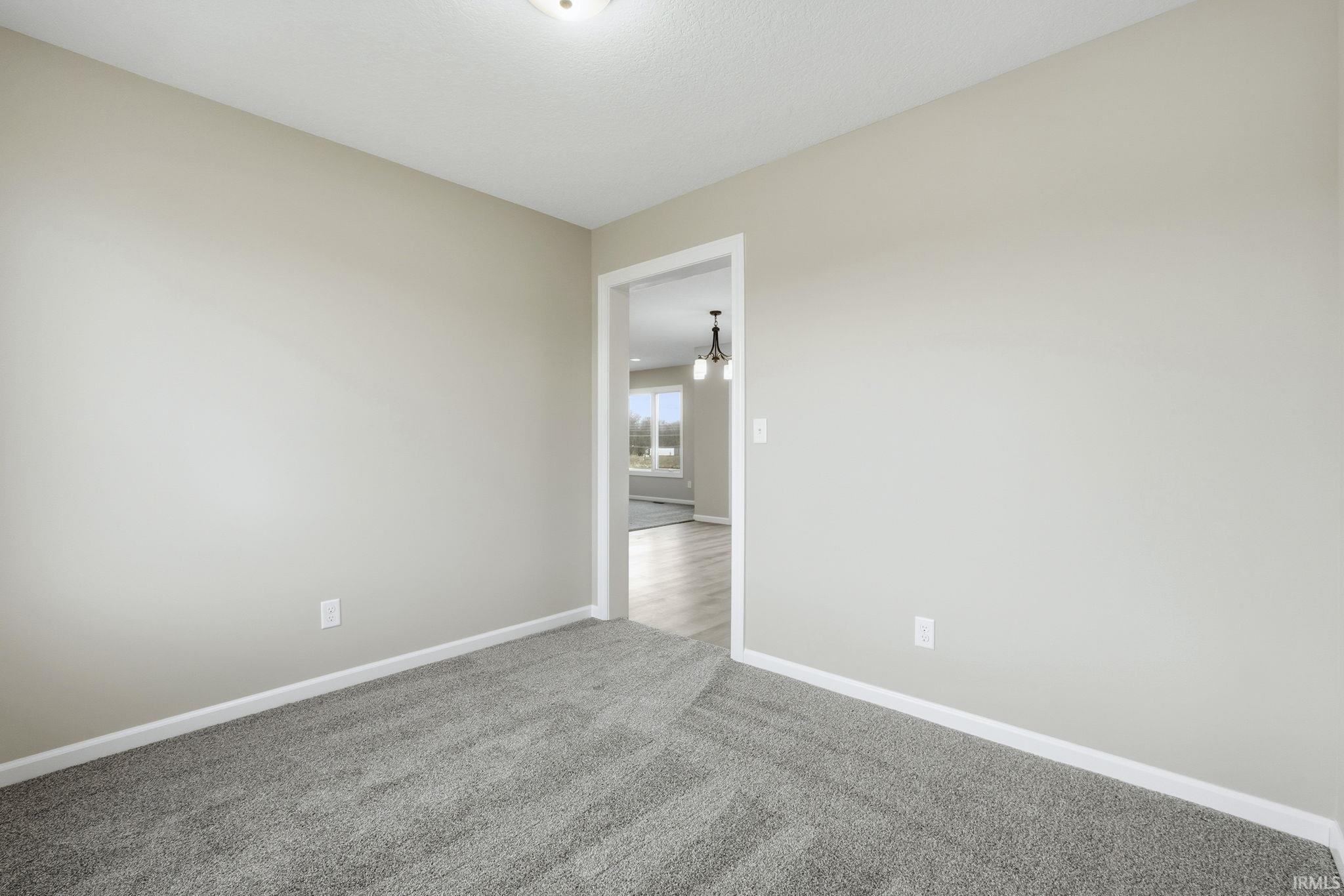 Spare room featuring carpet and a chandelier