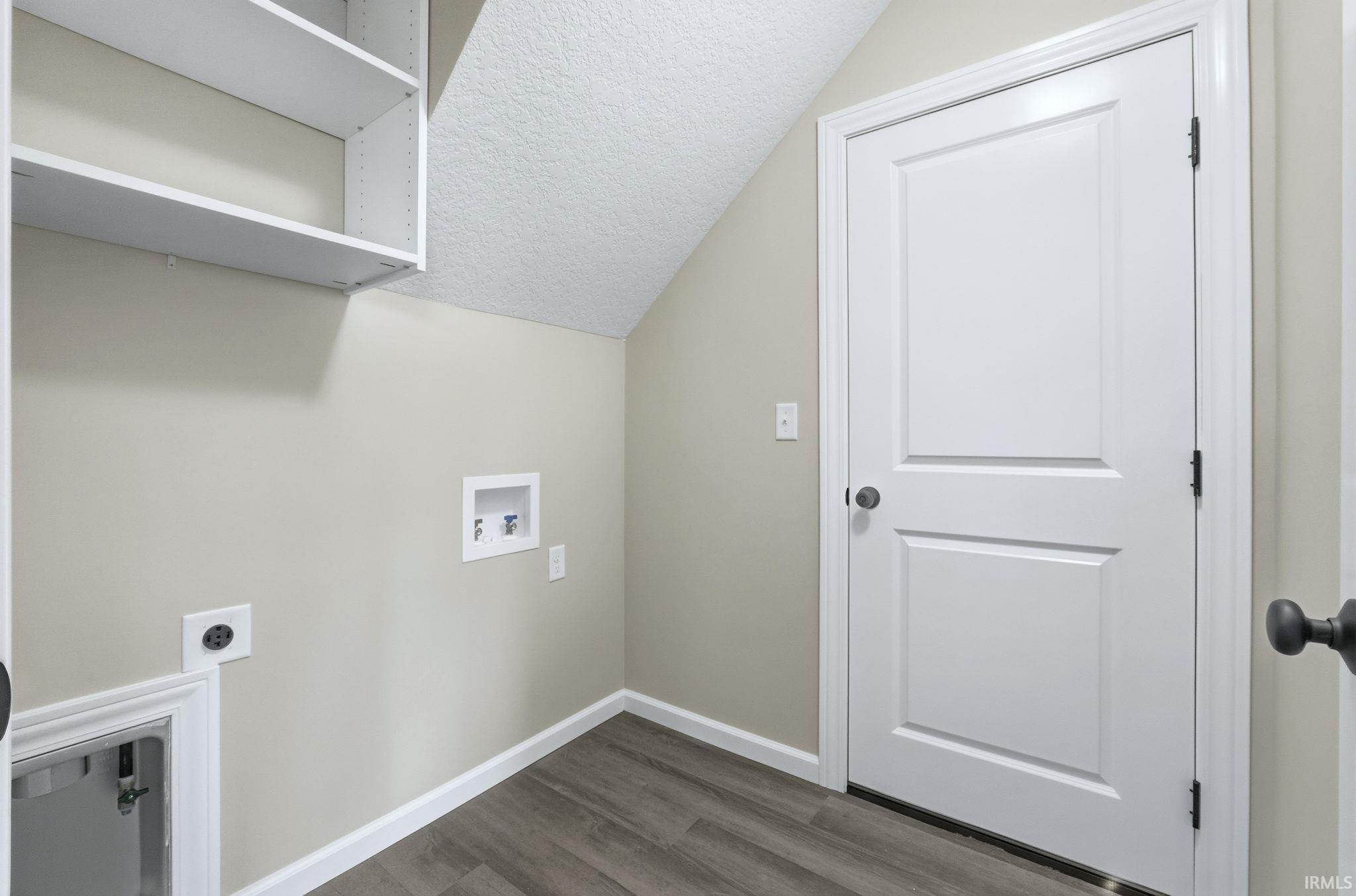 Laundry room with a textured ceiling, washer hookup, hookup for an electric dryer, dark wood-type flooring, and lofted ceiling
