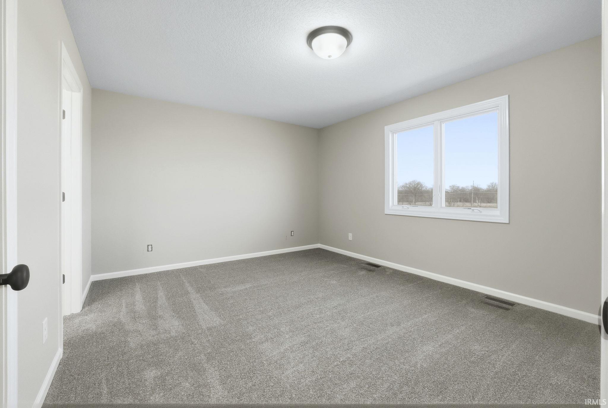 Carpeted empty room featuring baseboards and a textured ceiling