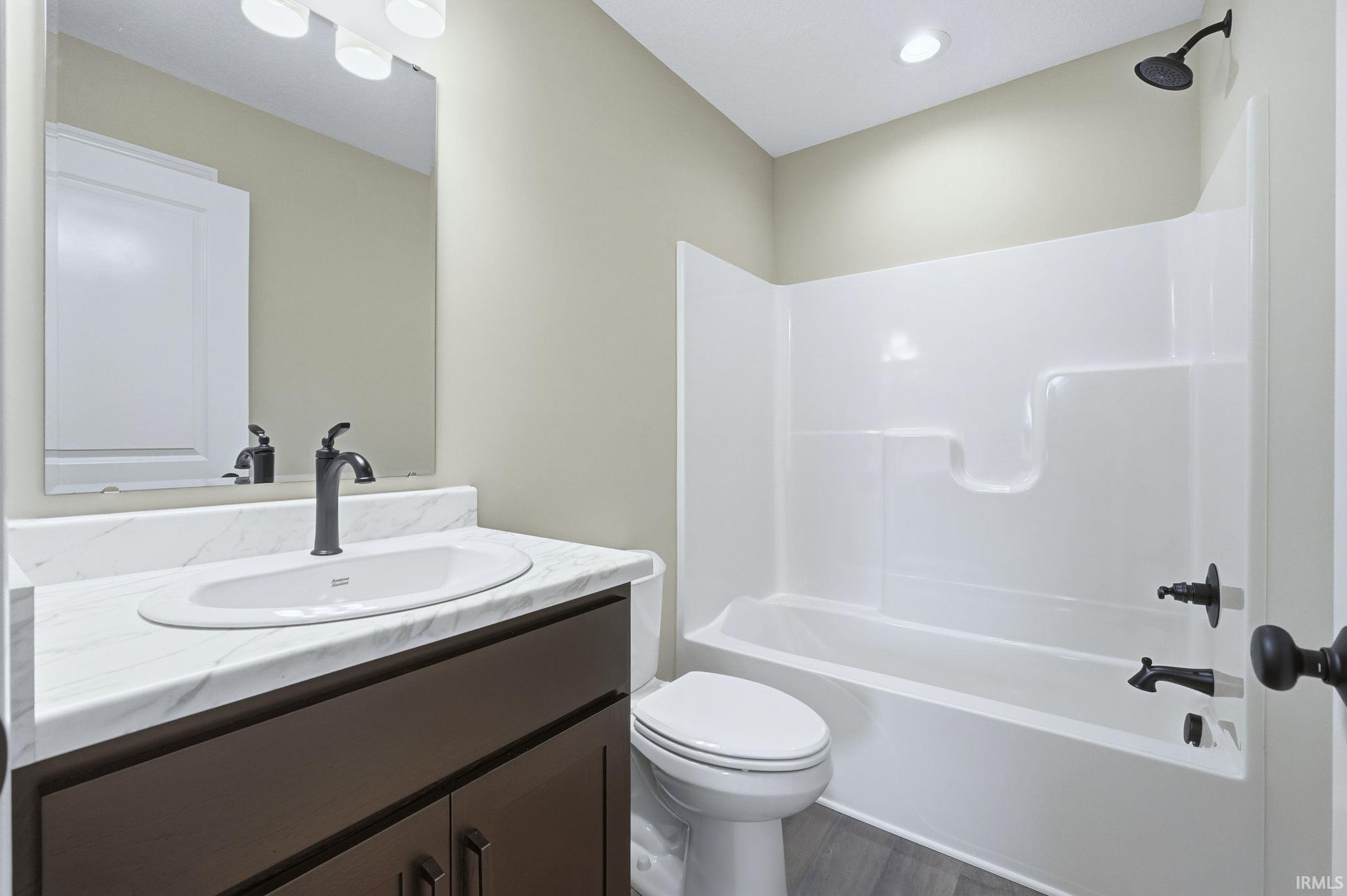 Full bathroom featuring vanity, shower / bath combination, and dark wood finished floors