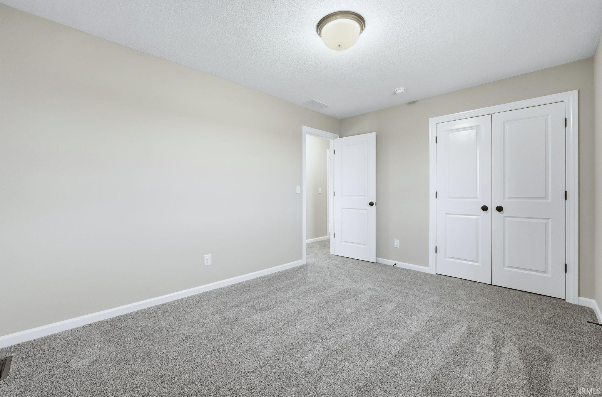 Unfurnished bedroom featuring a closet, carpet floors, and a textured ceiling