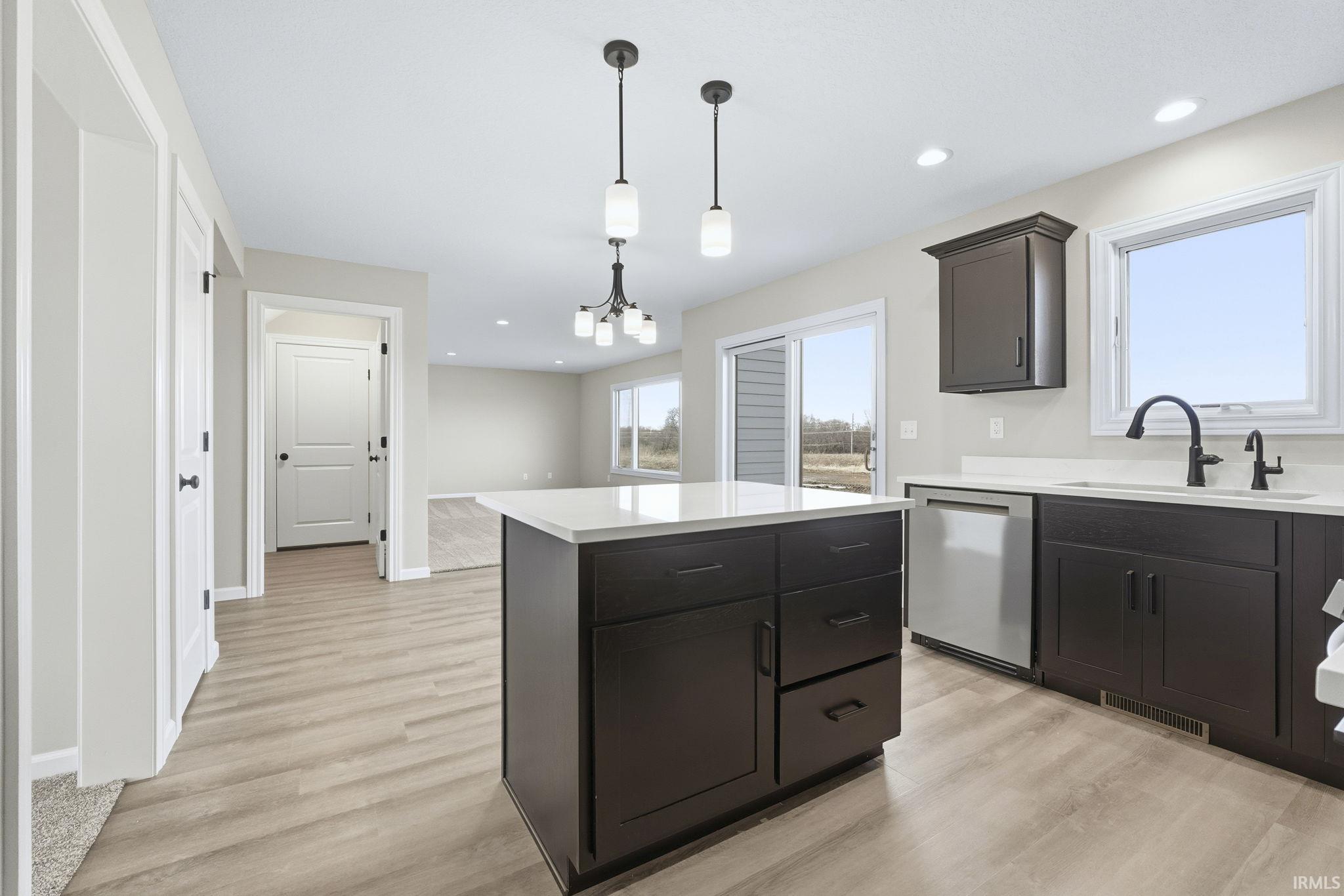 Kitchen featuring a kitchen island, hanging light fixtures, stainless steel dishwasher, light wood-style flooring, and recessed lighting